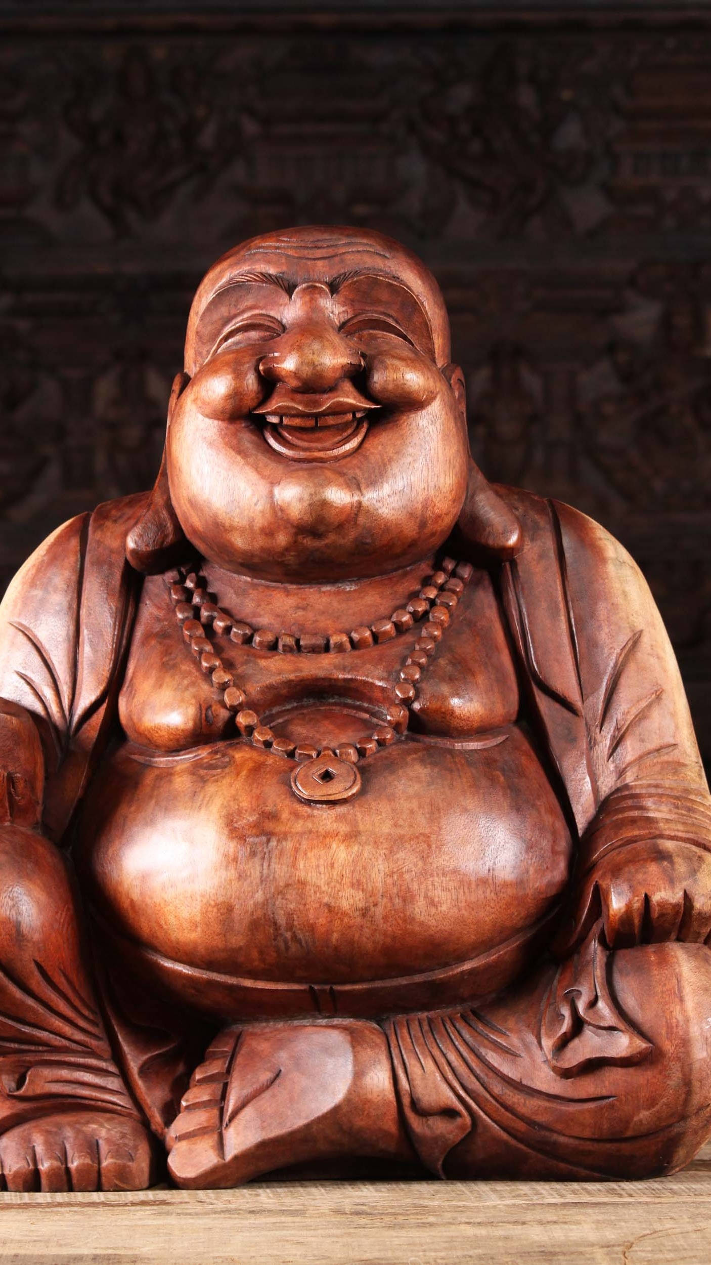 Statue Aesthetic 桌布 壁紙 — 一尊溫暖照明的笑佛木雕，表情歡樂，戴著珠鏈。