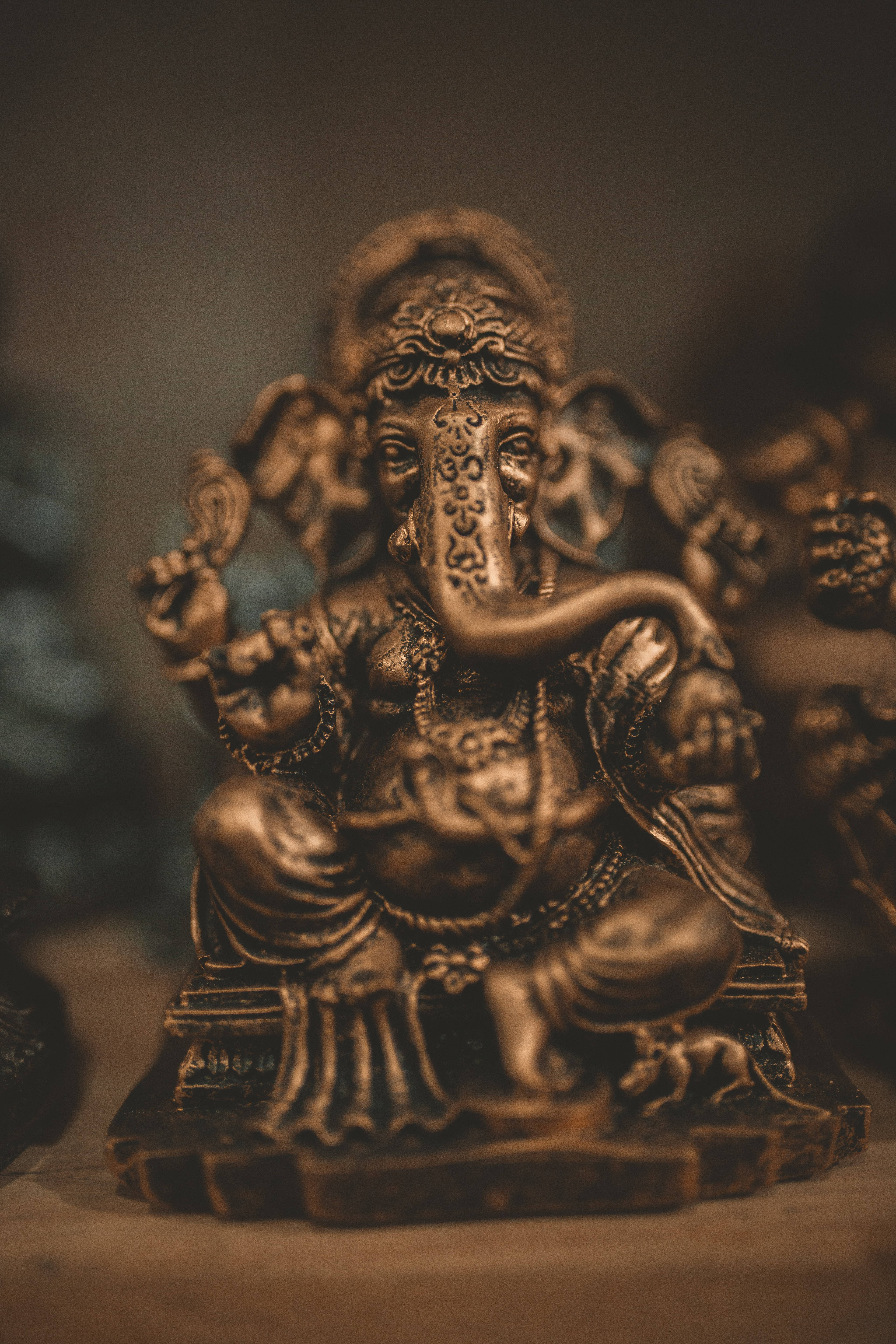 Ganesh 桌布 壁紙 — 一尊精細的青銅象頭神像安詳地坐著，帶有複雜的雕刻和優雅捲曲的長鼻子。
