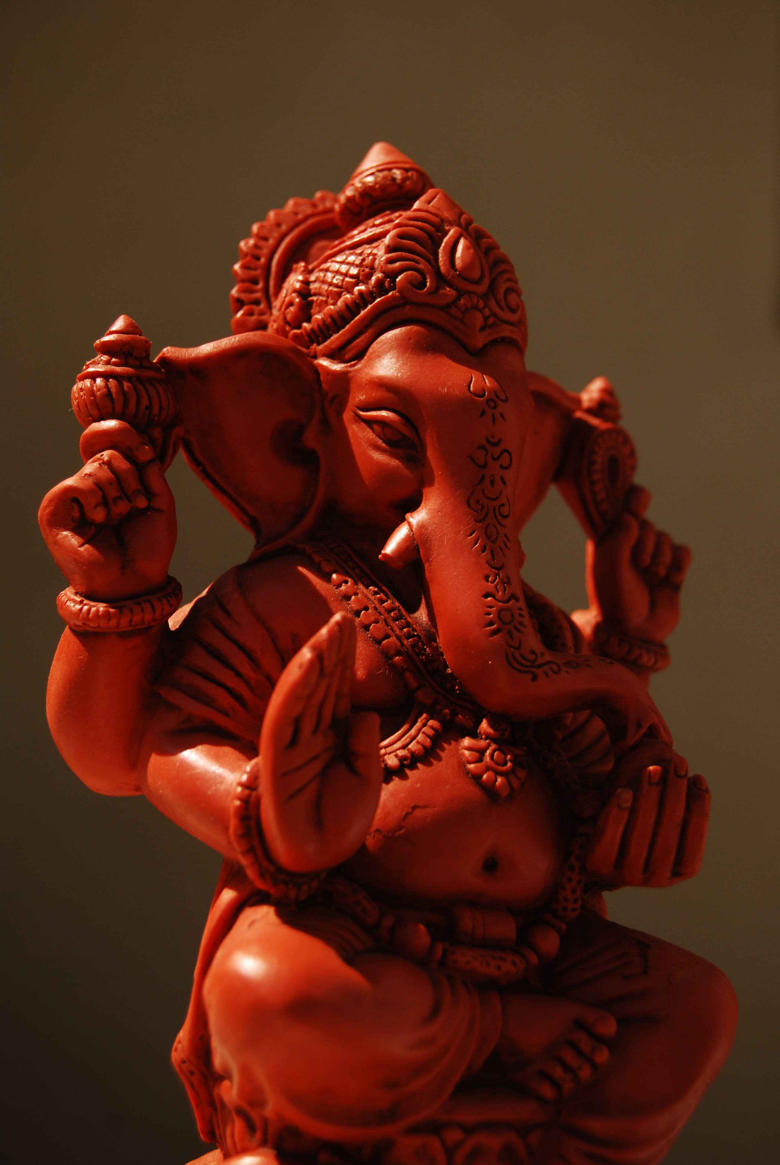 hindu iPhone 桌布 壁紙 — 一尊細節豐富的紅色赤陶象頭神像，雕刻精緻，表情寧靜。