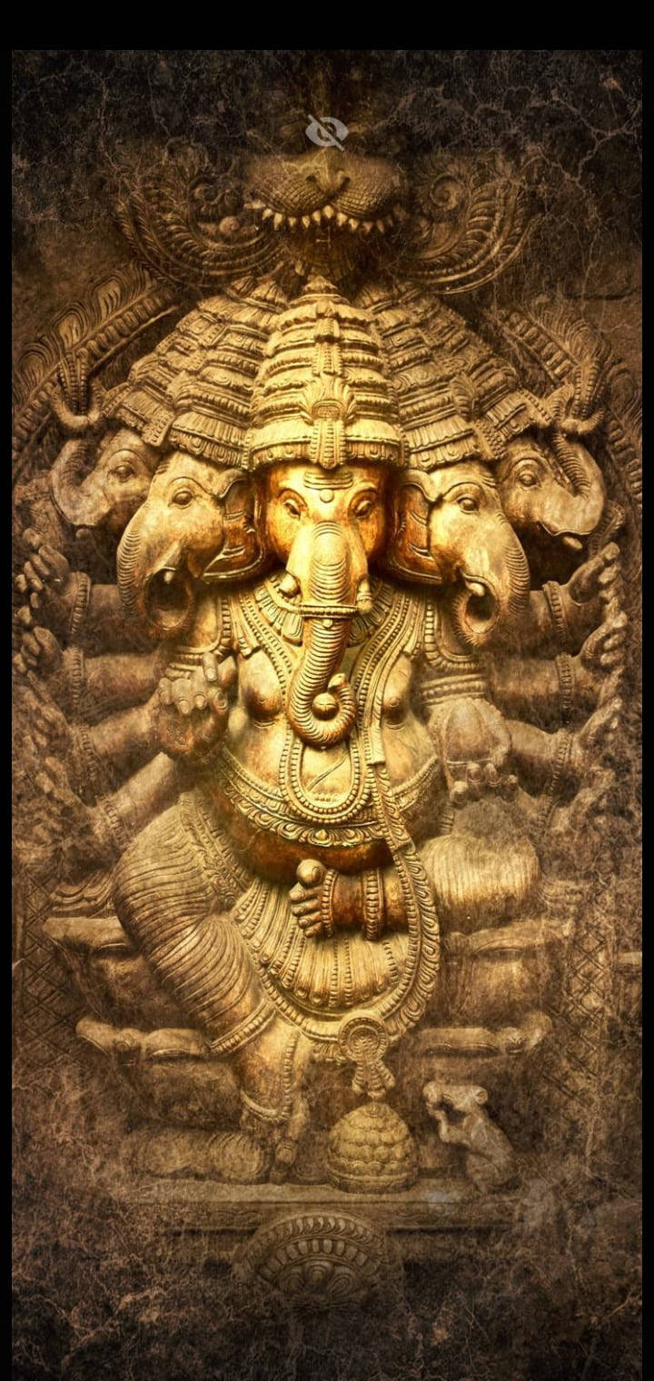 hindu iPhone 桌布 壁紙 — 一尊莊嚴的金色象頭神像，有多隻手臂和象頭，在深色紋理背景上雕刻出精細的細節。