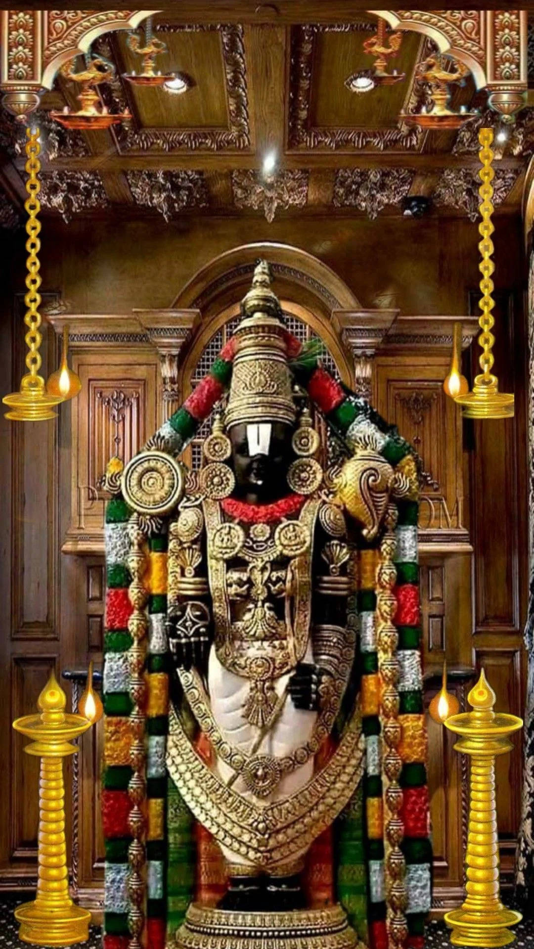 Vishnu 桌布 壁紙 — 一尊莊嚴的黑色神像，飾有金色飾物和彩色花環，矗立在裝飾華麗的木製寺廟神龕中，由懸掛的油燈照亮。