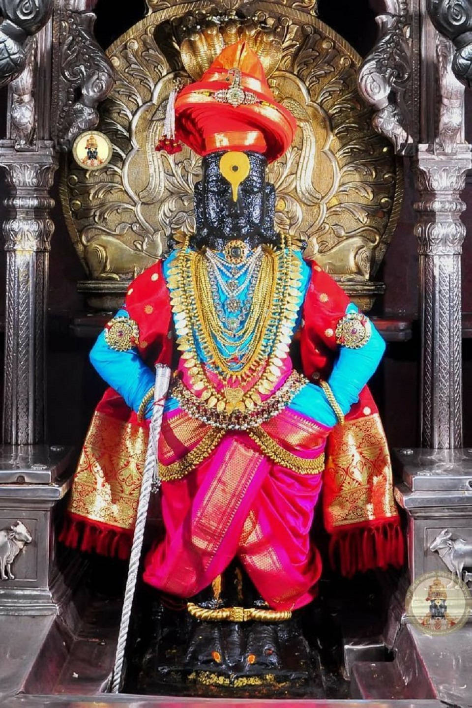 Hindu Temple 桌布 壁紙 — 一尊裝飾華麗的黑色神像，身穿鮮豔的紅、藍、金色長袍，威嚴地坐在華麗的金色寶座上。
