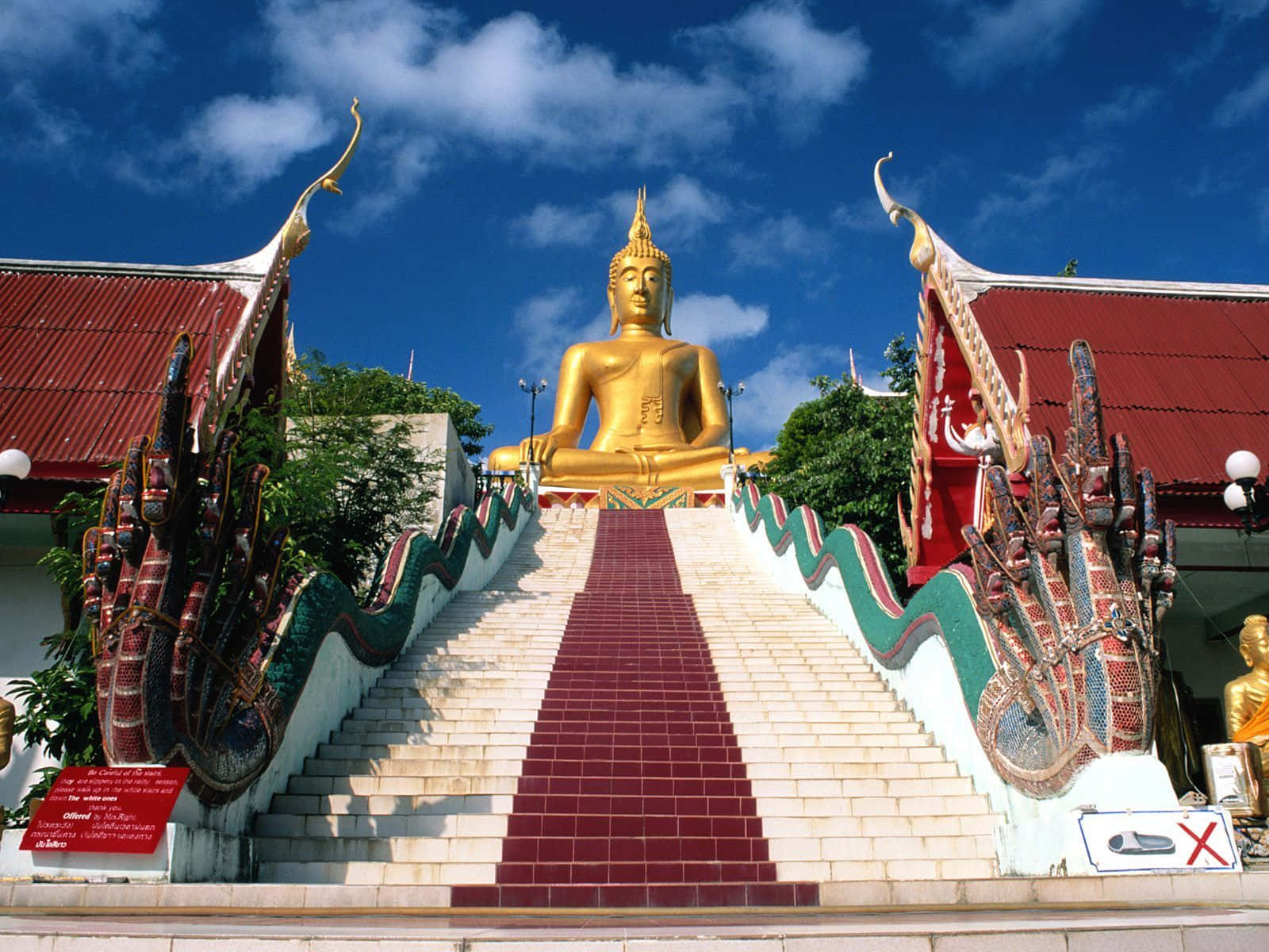 Thailand 桌布 壁紙 — 一尊金色佛像坐喺華麗龍欄杆嘅大樓梯頂，喺明亮藍天之下。