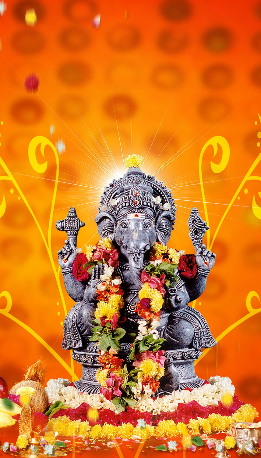 hindu iPhone 桌布 壁紙 — 一尊閃亮的銀色象神像，飾以色彩繽紛的鮮花，坐在花卉底座上，背景是帶有金色漩渦的發光橙色。