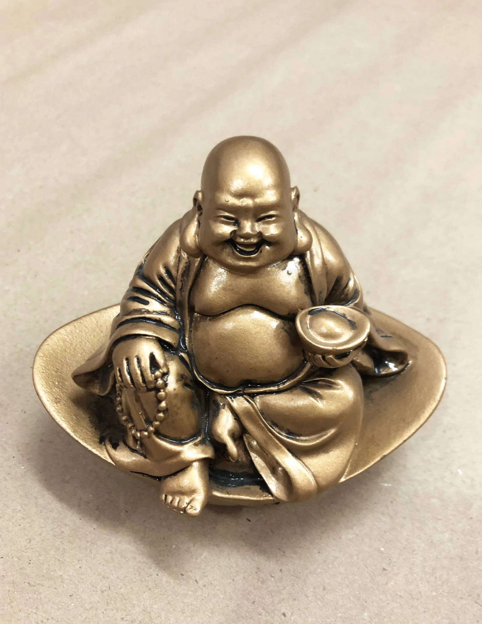 Statue Aesthetic 桌布 壁紙 — 一尊閃亮的青銅笑佛盤腿坐在碟子上，手持碗和念珠。