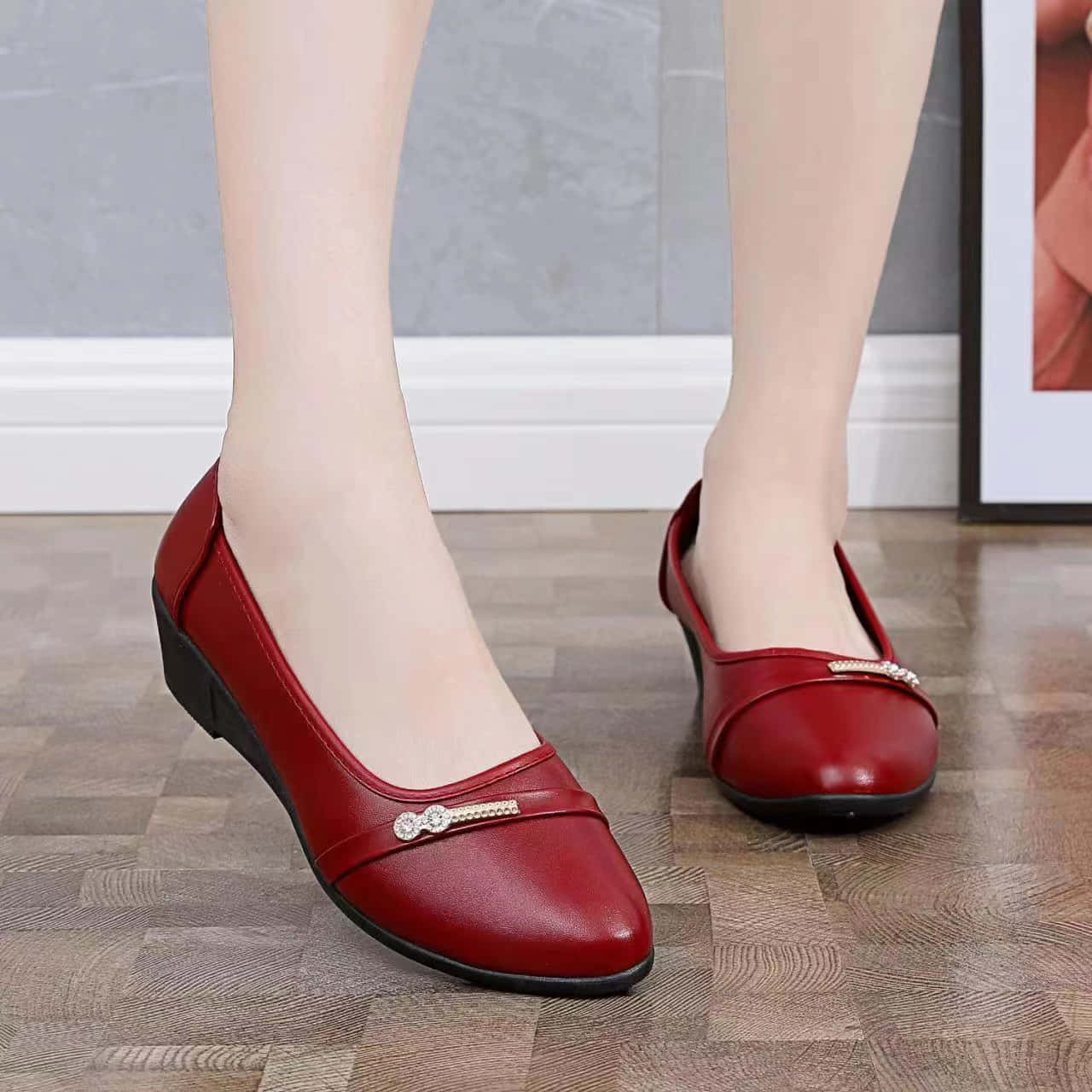 Red Shoes 桌布 壁紙 — 一對優雅的紅色皮革女裝平底鞋，飾有寶石帶，放在灰色牆壁前的木地板上。