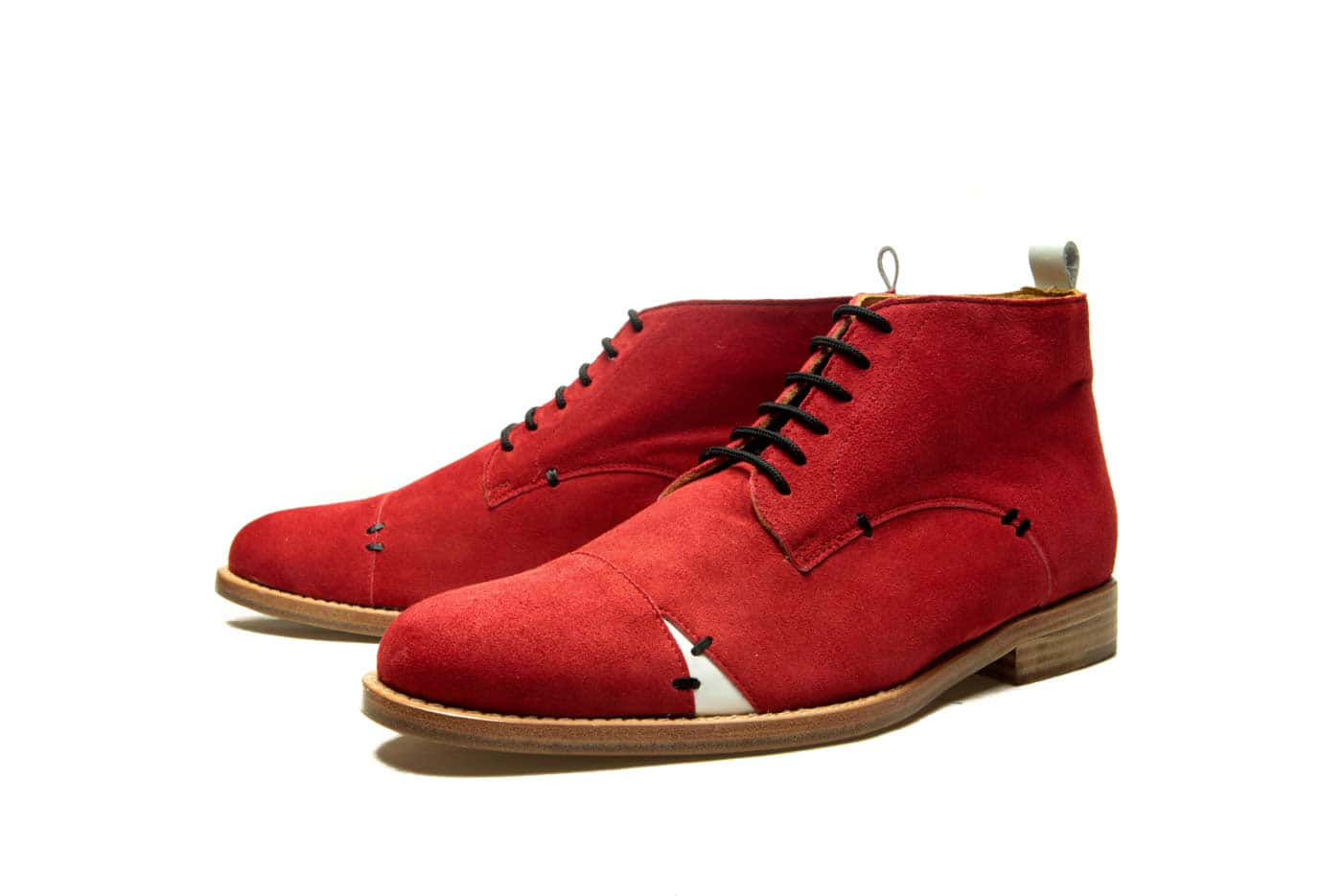 Red Shoes 桌布 壁紙 — 一對大膽的紅色麂皮查卡靴，配有黑色鞋帶和白色鞋頭裝飾，背景為純白色。