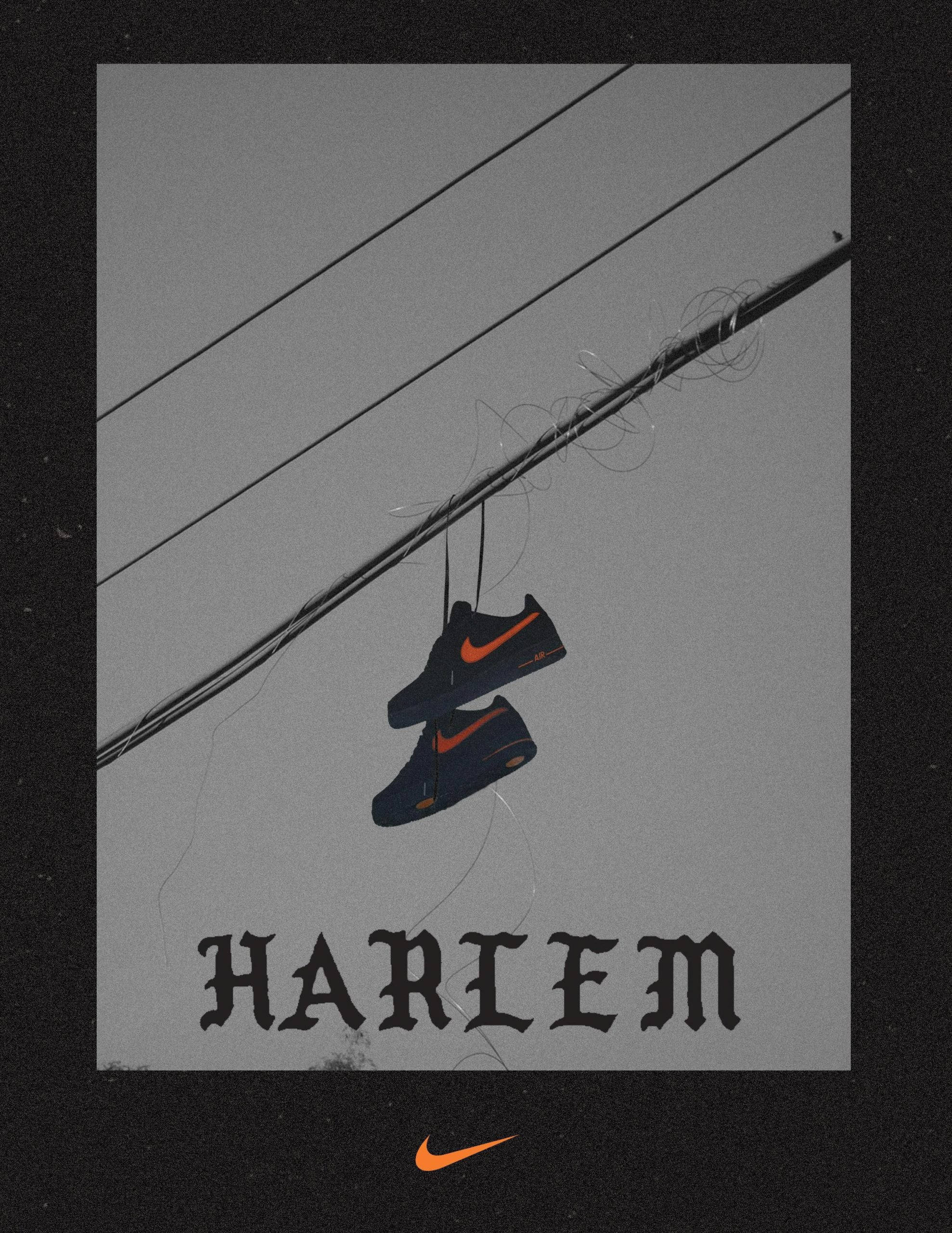 Nike VLONE Harlem 壁紙 — 一對帶有橙色swoosh的黑色Nike運動鞋掛在纏繞的電線上，背景是灰色天空，下方有'HARLEM'文字。