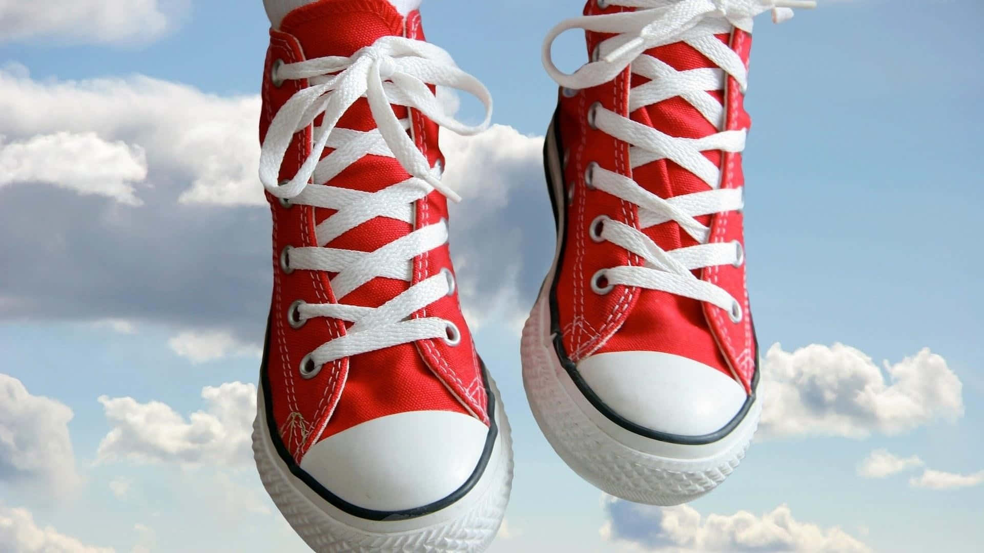 Red Shoes 桌布 壁紙 — 一對帶有白色鞋帶的紅色高筒運動鞋在明亮的藍天和蓬鬆的白雲中漂浮。