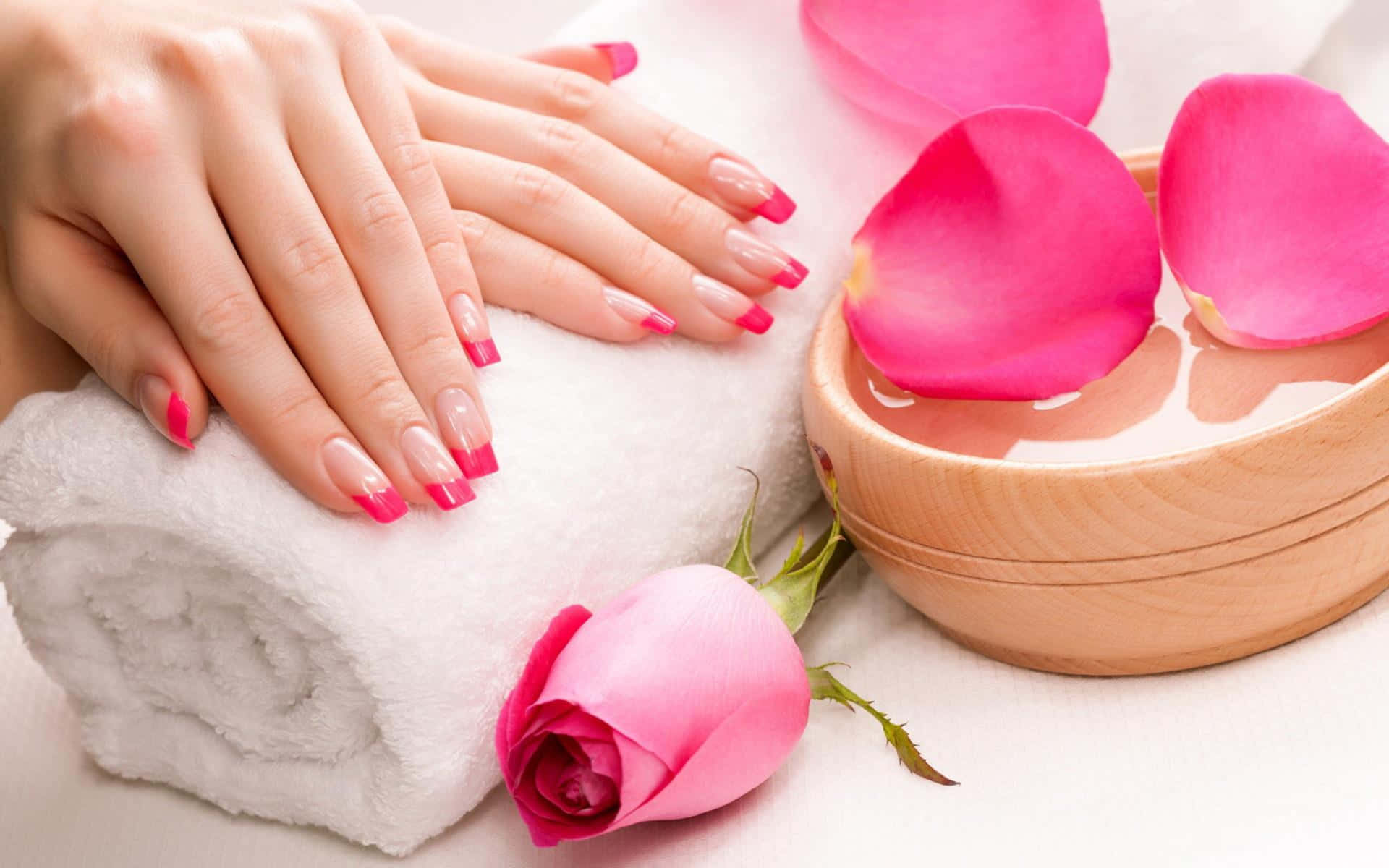 Pink Nails 桌布 壁紙 — 一對帶有粉紅色美甲的手放在白色毛巾上，旁邊是一個木碗，裡面有水、玫瑰花瓣和新鮮的粉紅玫瑰。