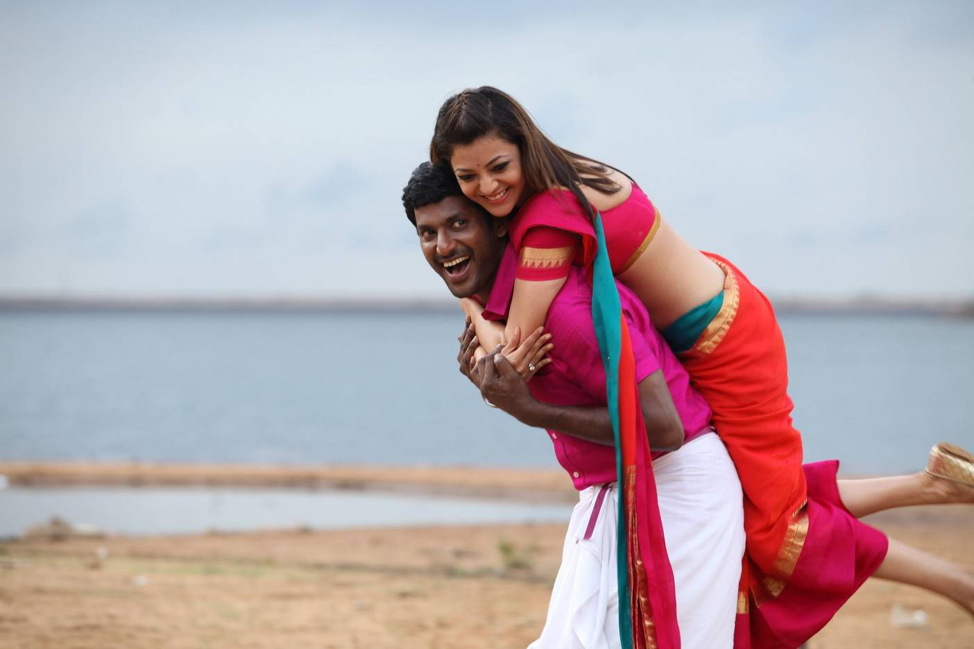 Tamil Actors HD 桌布 壁紙 — 一對快樂的情侶在陰天下的平靜湖邊分享一個頑皮的揹背時刻。