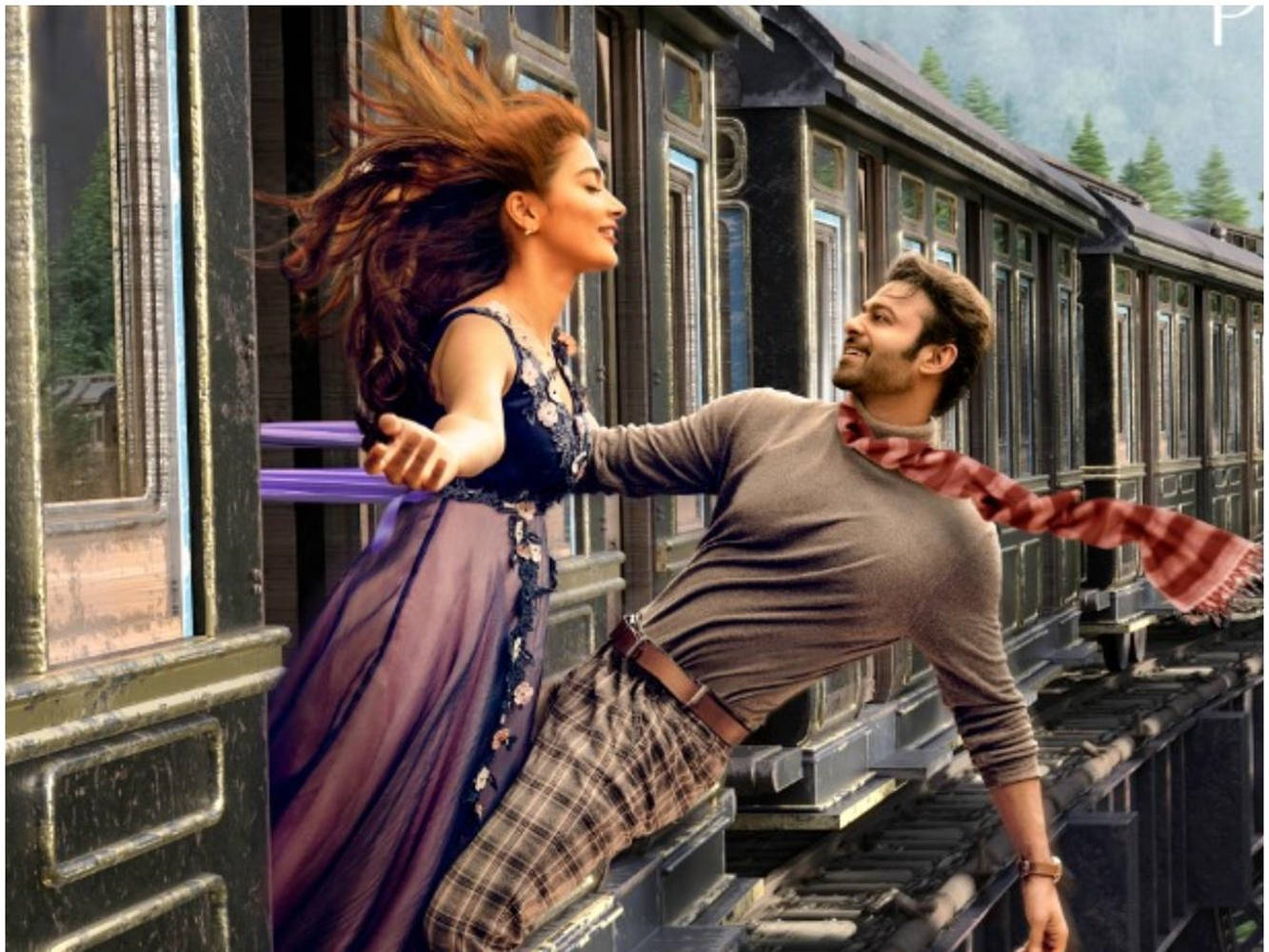 Prabhas 桌布 壁紙 — 一對快樂的情侶從行駛中的火車車窗探出身子，頭髮和圍巾隨風飄揚，背景是森林覆蓋的山脈。