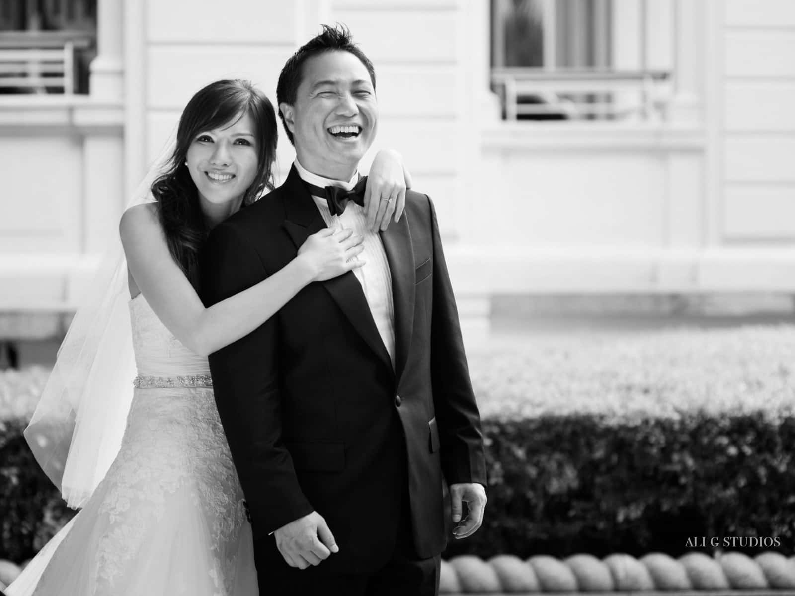 Black And White Wedding 桌布 壁紙 — 一對快樂的黑白婚禮新人在經典建築前戶外一起大笑。