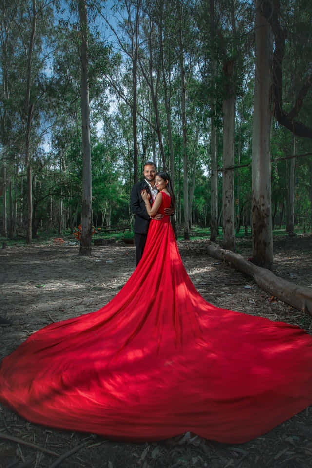 Red Wedding 桌布 壁紙 — 一對情侶在森林中擁抱，女士鮮紅色的長裙戲劇性地在森林地面上飄揚。