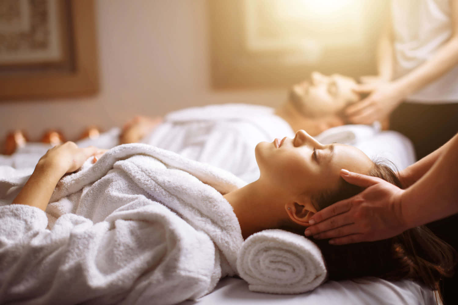 一位女士在水療中心接受頭部按摩，陽光灑入。
