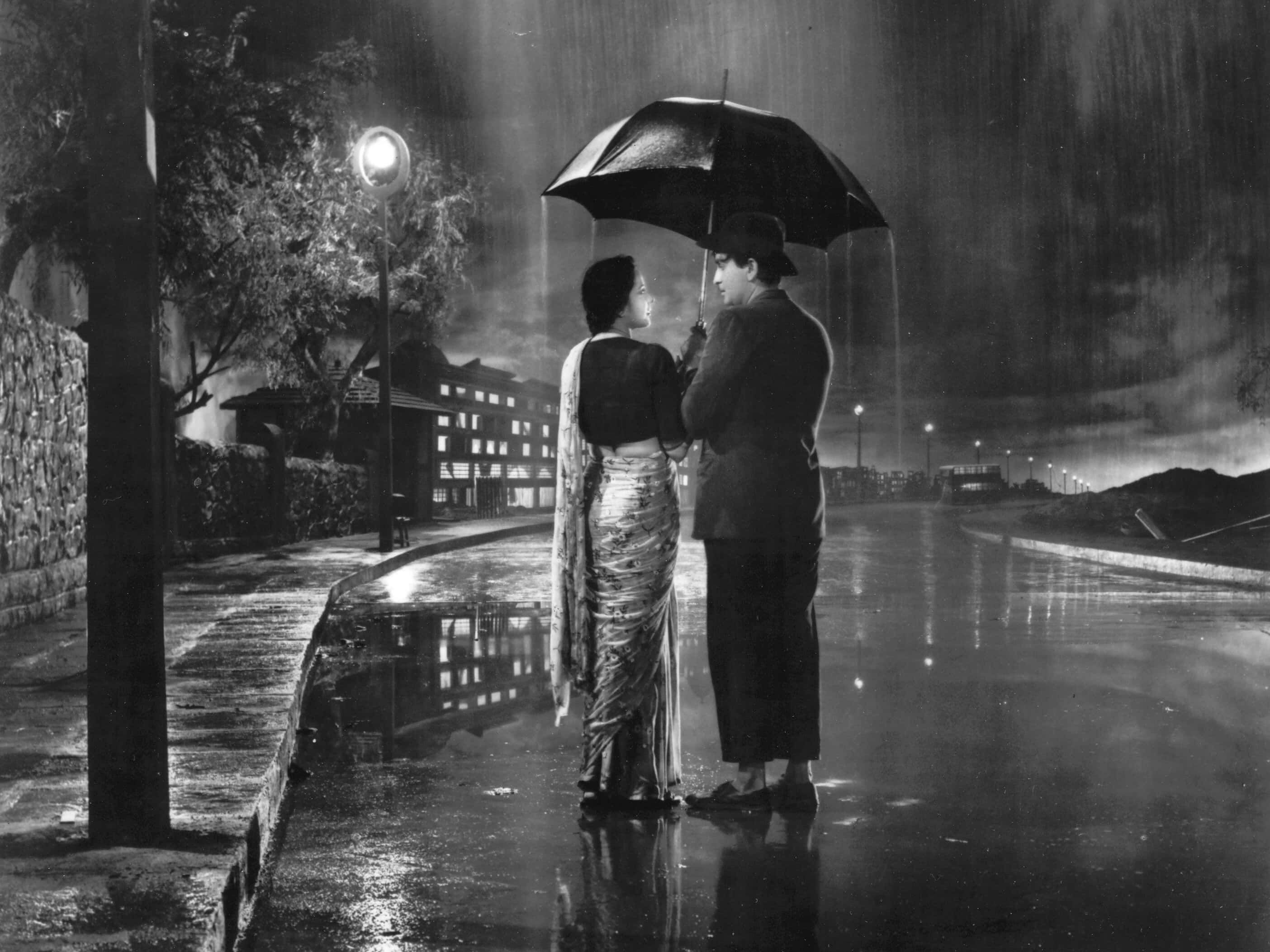 Classic Movie 桌布 壁紙 — 一對情侶在雨夜的路燈下共享一把傘，他們的倒影在濕漉漉的人行道上閃爍。