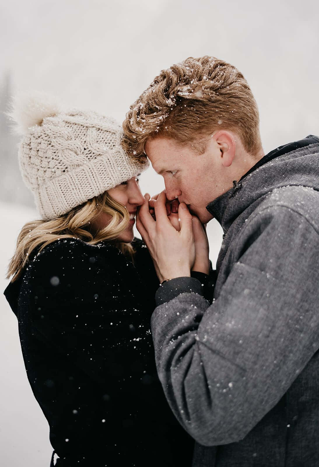 Winter Photography 桌布 壁紙 — 一對情侶在飄雪中額頭相觸、雙手緊握，分享親密時刻