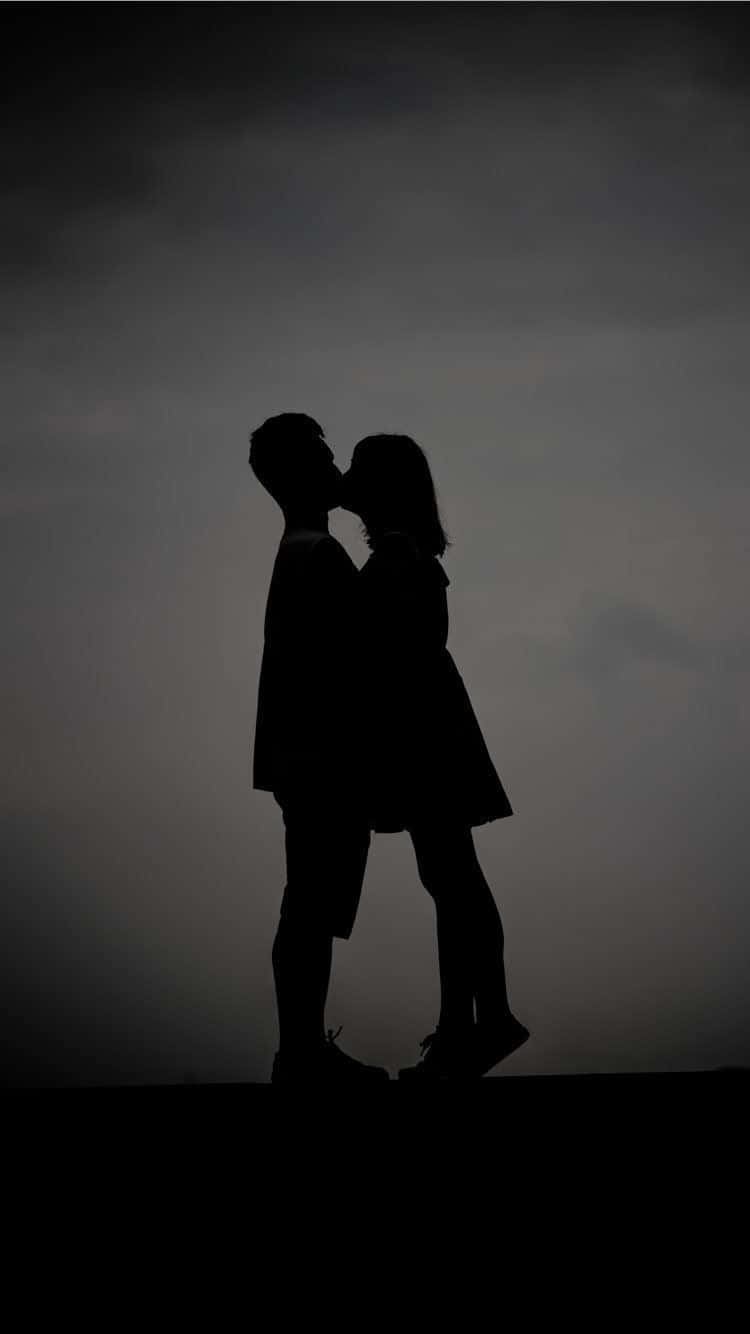 Lovers 桌布 壁紙 — 一對情侶在黃昏時分陰沉灰暗的天空下接吻的浪漫剪影。
