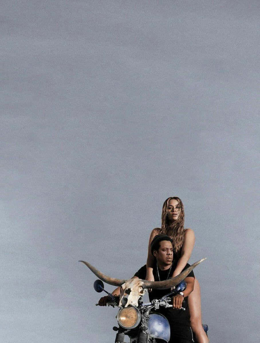Beyoncé 桌布 壁紙 — 一對情侶騎著一輛裝飾有長角牛頭骨的訂製電單車，背景是廣闊的灰色天空。