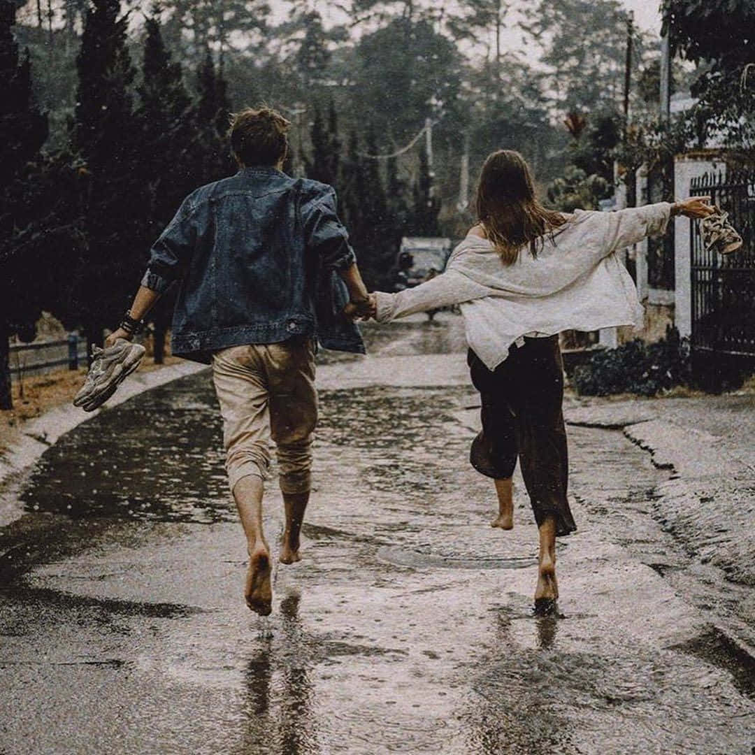 兩個人在雨中赤腳手牽手跑過濕漉漉的街道。