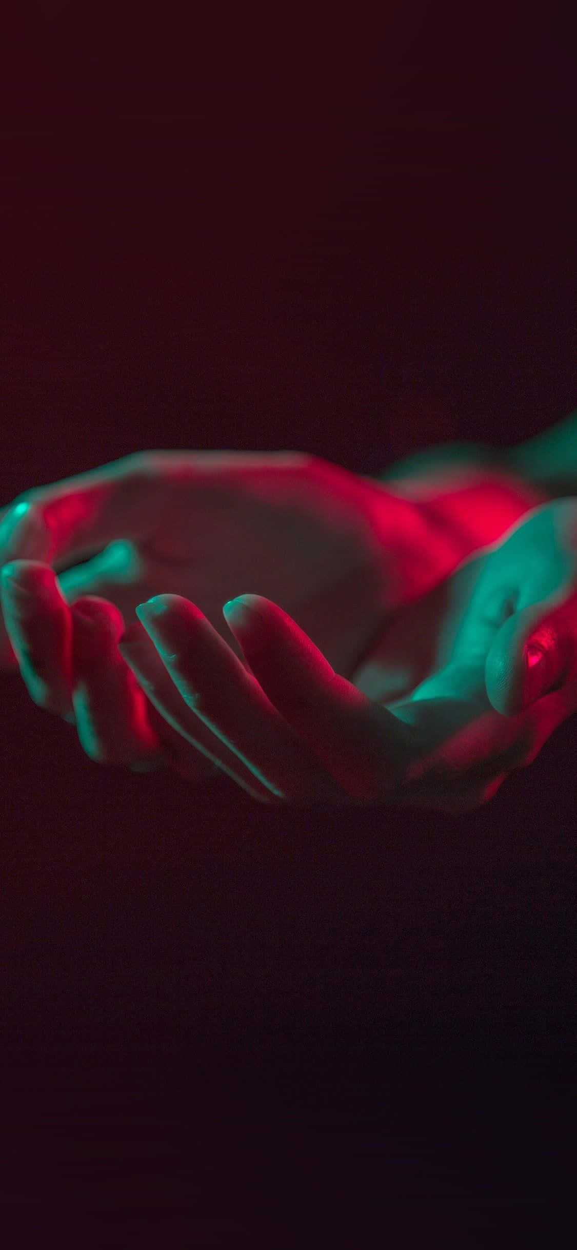 hand 桌布 壁紙 — 一對手捧開放在戲劇性的紅色和青色霓虹燈光下，背景為深色。