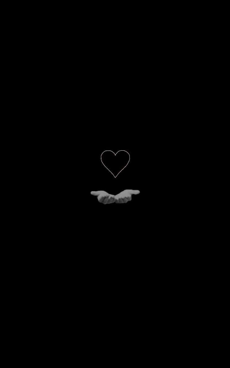 Aesthetic Black Heart 桌布 壁紙 — 一對手輕輕捧著一個發光的白色心形輪廓，背景是純黑色。