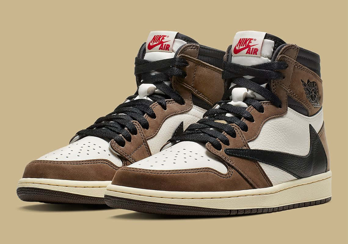 Travis Scott Jordan 1 桌布 壁紙 — 一對棕色、白色和黑色的高筒運動鞋，帶有紅色Nike Air品牌標誌，背景為米色。