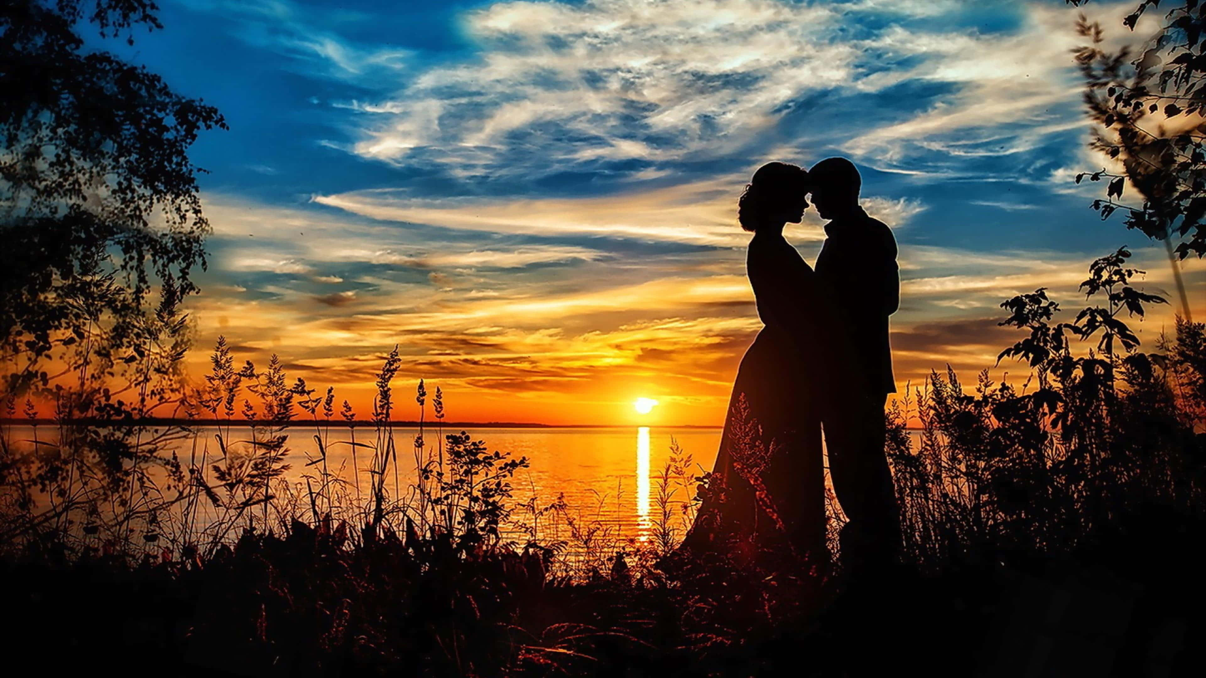 Beach Lovers 桌布 壁紙 — 一對浪漫情侶在平靜湖面上映照著金色光芒的夕陽下剪影。