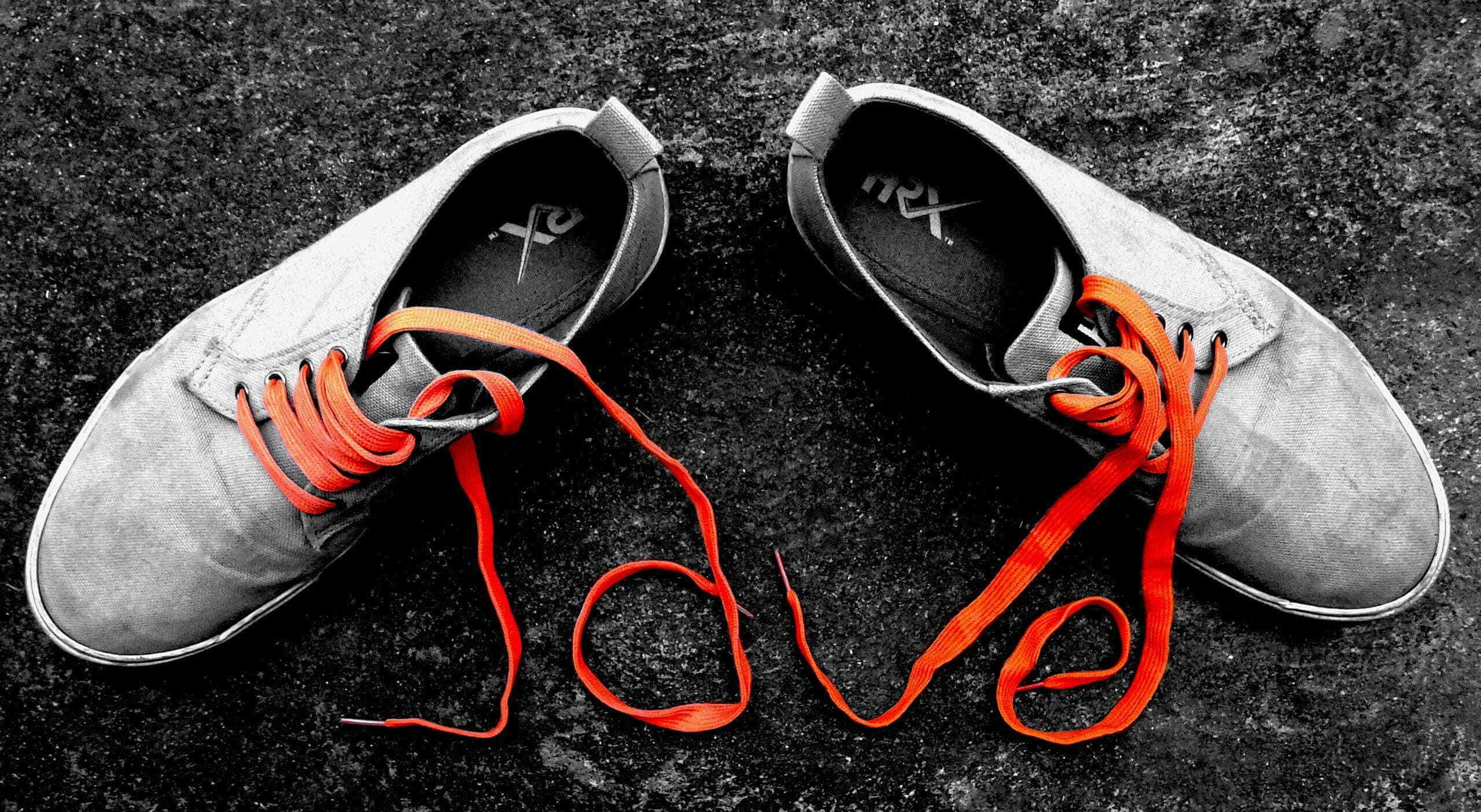 Cute Shoes 桌布 壁紙 — 一對灰色運動鞋，帶有鮮豔的橙色鞋帶，在深色紋理表面上排列成 love 字樣。