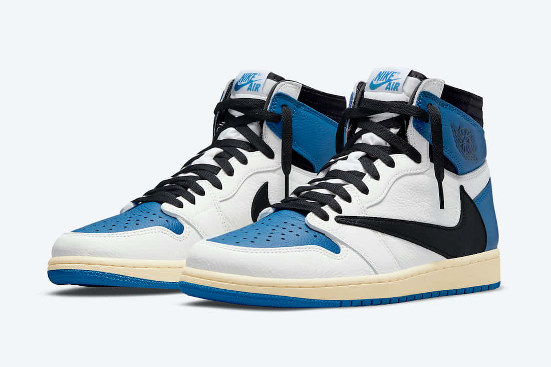Travis Scott Jordan 1 桌布 壁紙 — 一對白色、藍色和黑色的高筒運動鞋，帶有Nike Air品牌標誌和穿孔鞋頭。