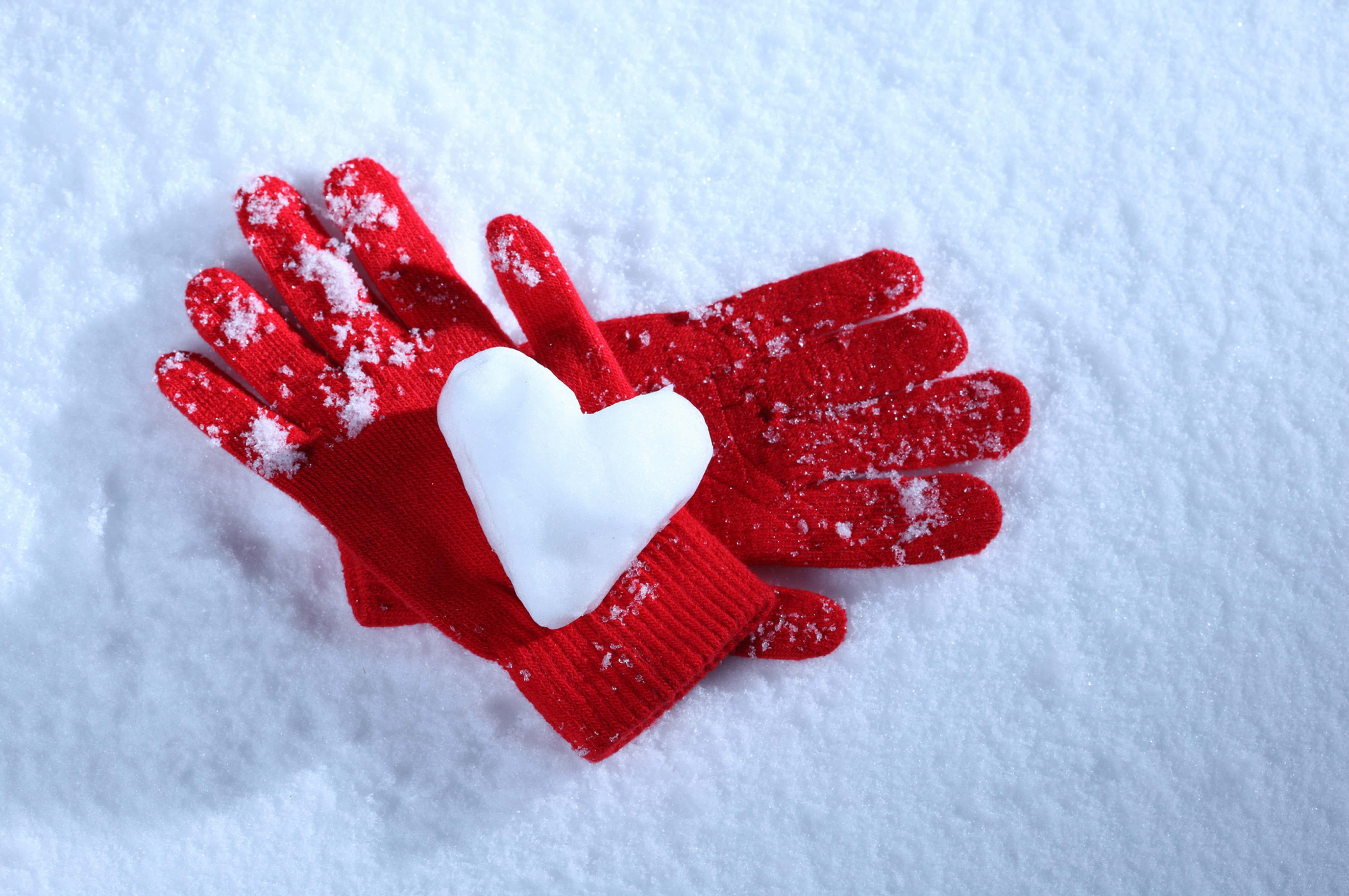 Mittens 桌布 壁紙 — 一對紅色針織手套放在新雪上，中間夾著一個白色的雪心心。