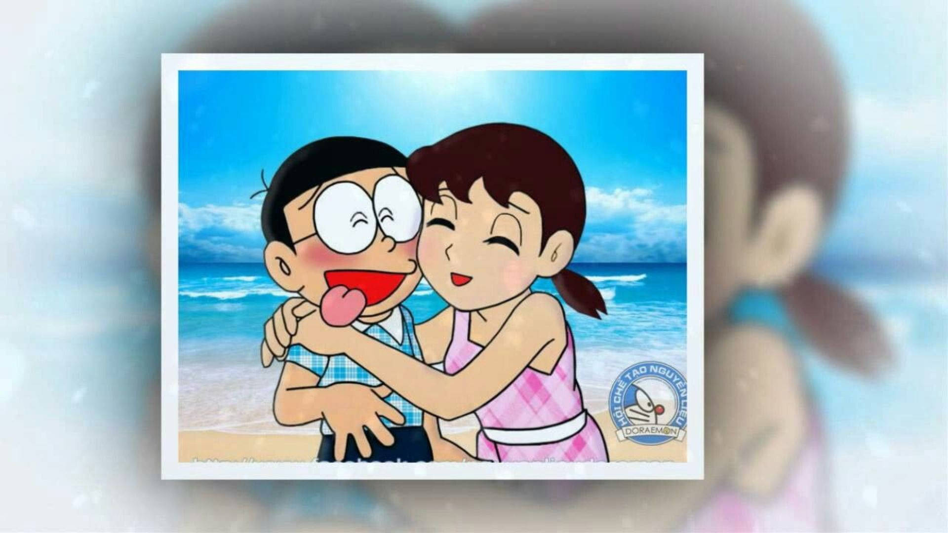 nobita shizuka love 桌布 壁紙 — 一對開心的動漫情侶在陽光明媚的海灘上擁抱，背後是藍色的海浪和晴朗的天空。