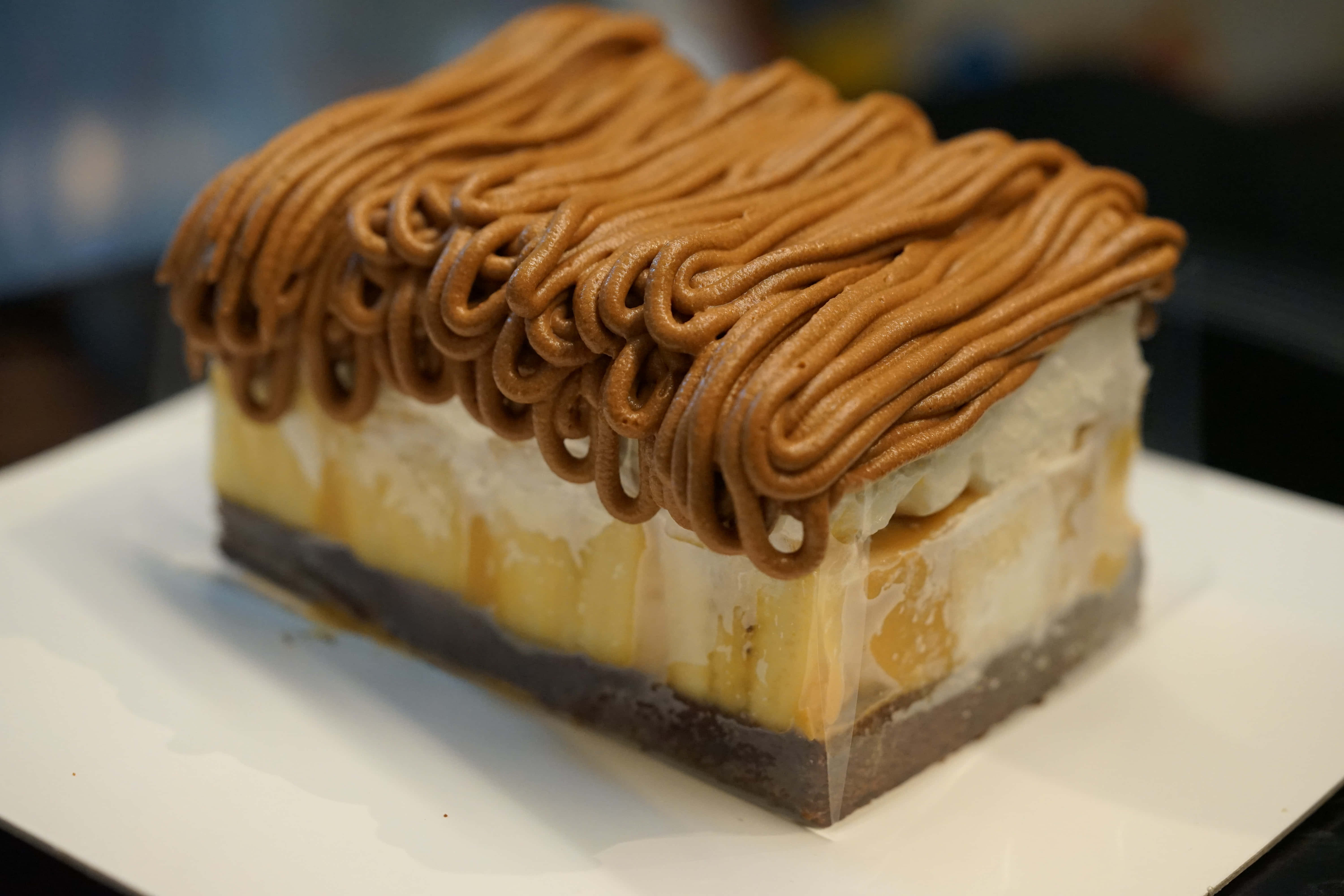 Caramel 桌布 壁紙 — 一層層的長方形甜點，帶有焦糖漩渦和奶油餡料，放在白色盤子上。