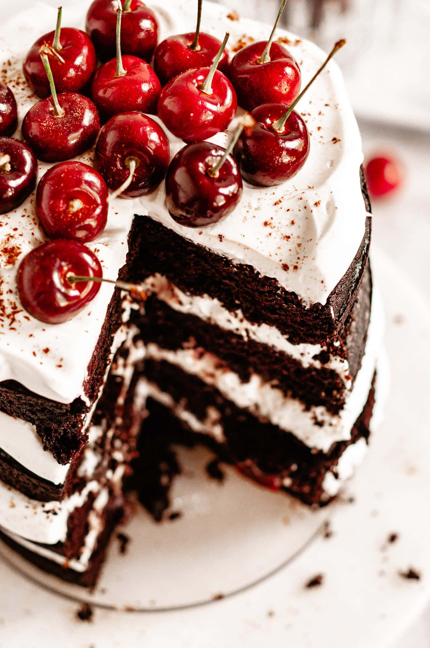 Black Forest Cake 桌布 壁紙 — 一層層頹廢的朱古力蛋糕，上面鋪滿閃亮的紅櫻桃，撒上可可粉。