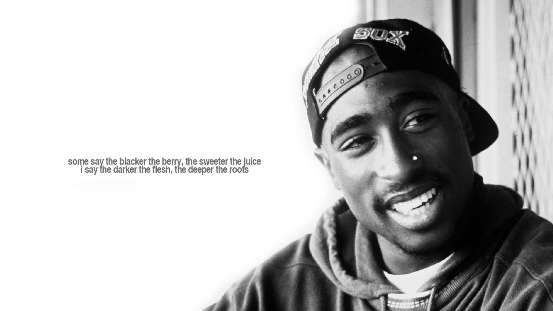 Tupac 桌布 壁紙 — 一幅Tupac Shakur的黑白肖像，他戴著向後的帽子，溫暖地微笑，圖像上覆蓋著文字。
