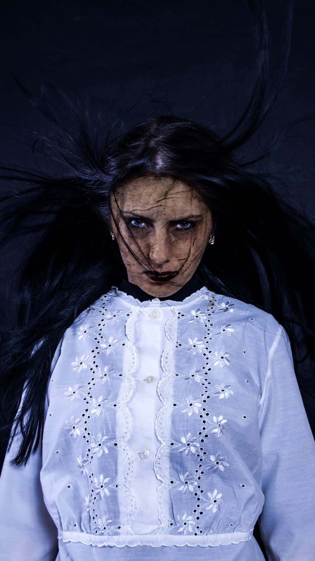 Horror Costumes 桌布 壁紙 — 一幅令人難忘的肖像畫，描繪一位皮膚蒼白、黑髮、身穿白色蕾絲襯衫的女性，背景為黑色。