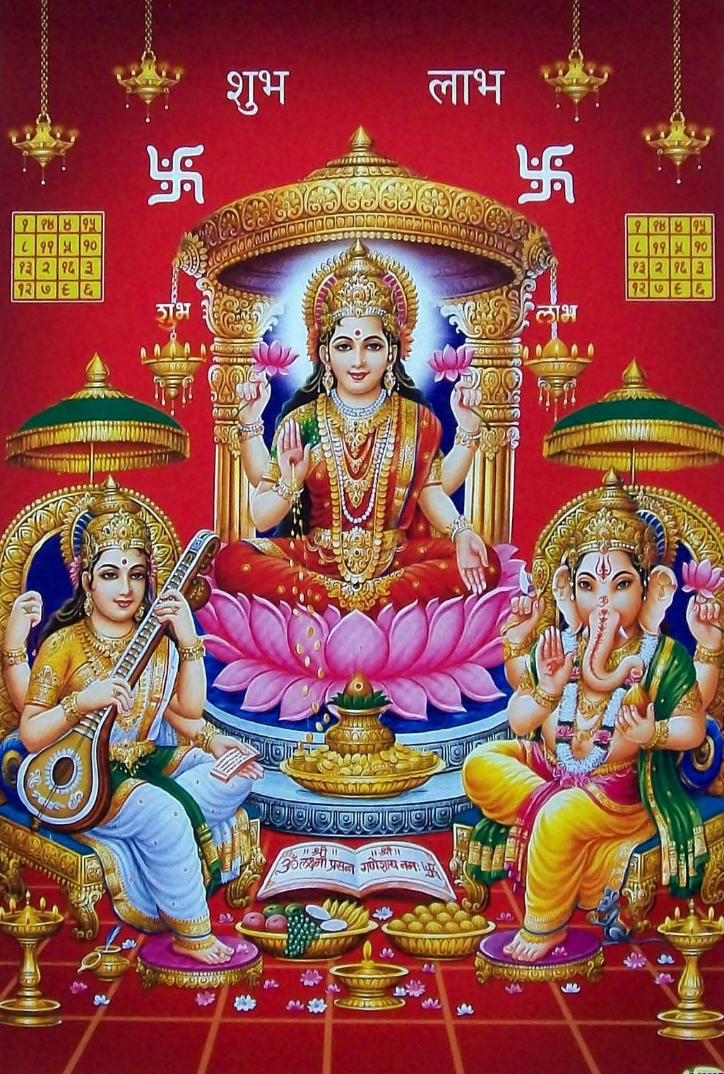 Hindu God 桌布 壁紙 — 一幅充滿活力的印度教神祇插圖，拉克什米坐在粉紅色蓮花上，兩側是薩拉斯瓦蒂和象頭神，背景為紅色，帶有金色點綴和梵文文字。