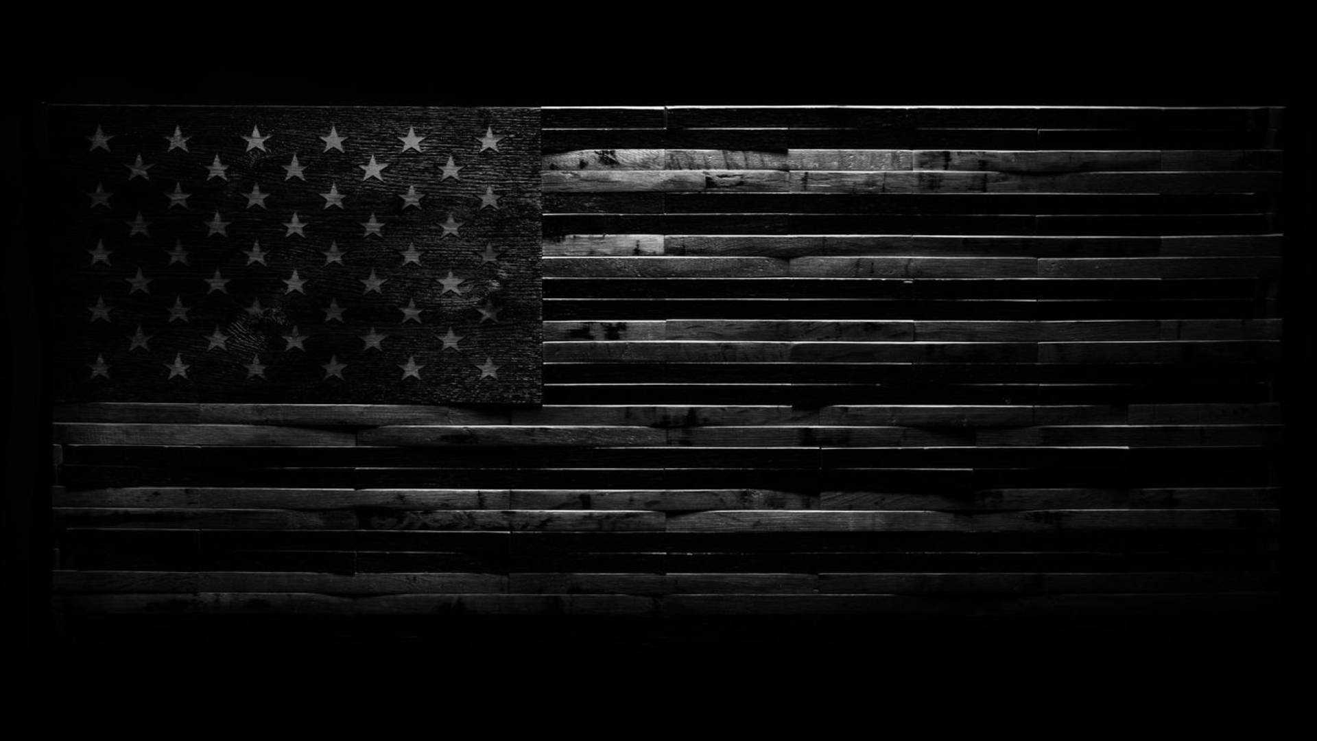 Black American Flag 桌布 壁紙 — 一幅單色美國國旗蝕刻在風化的木板上，帶有深色陰影和木紋紋理。