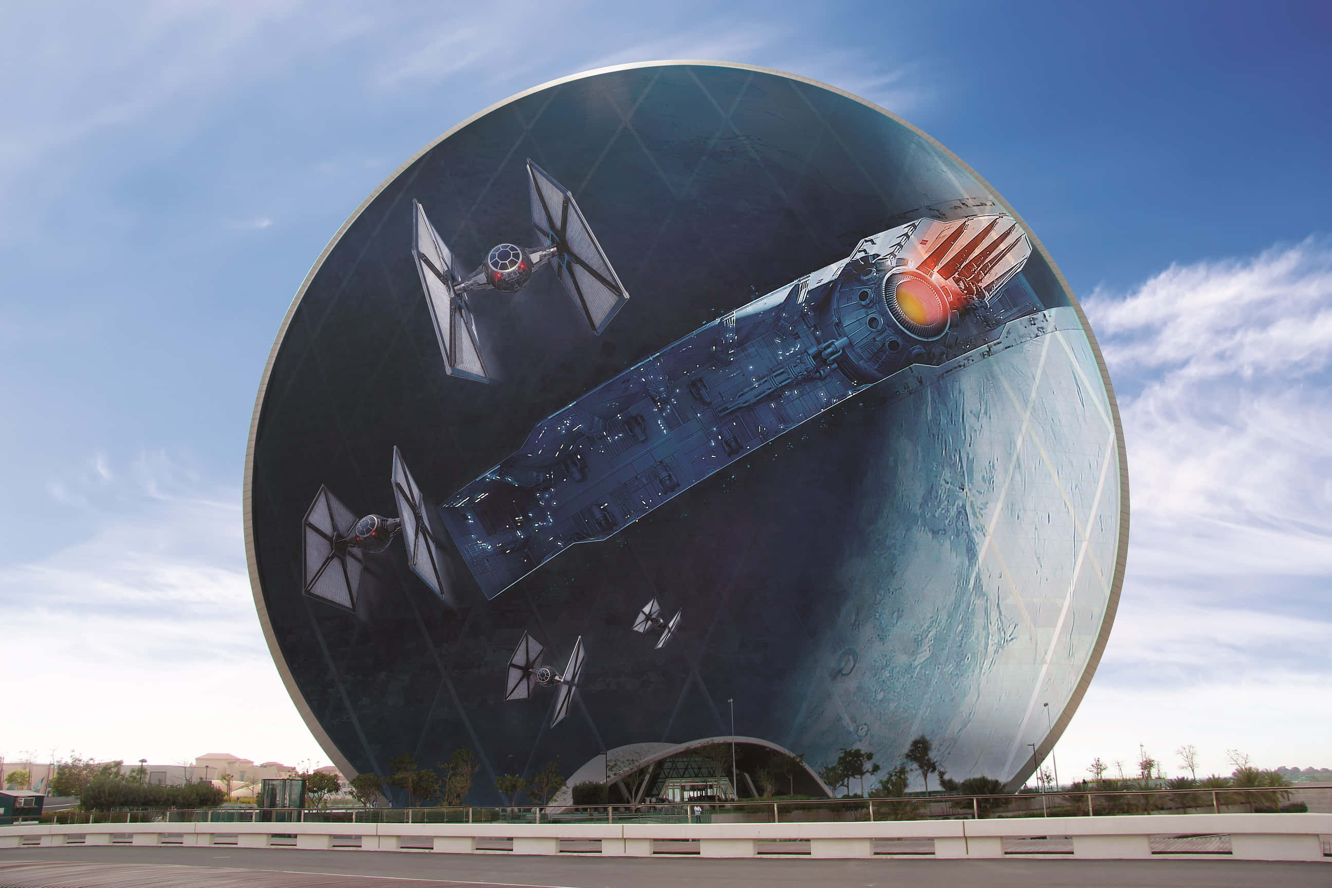 Starkiller Base 桌布 壁紙 — 一幅巨大的圓形壁畫描繪了《星球大戰》的TIE戰機和星際毀滅者，背景是星空，位於一座現代建築上，上方是藍天。