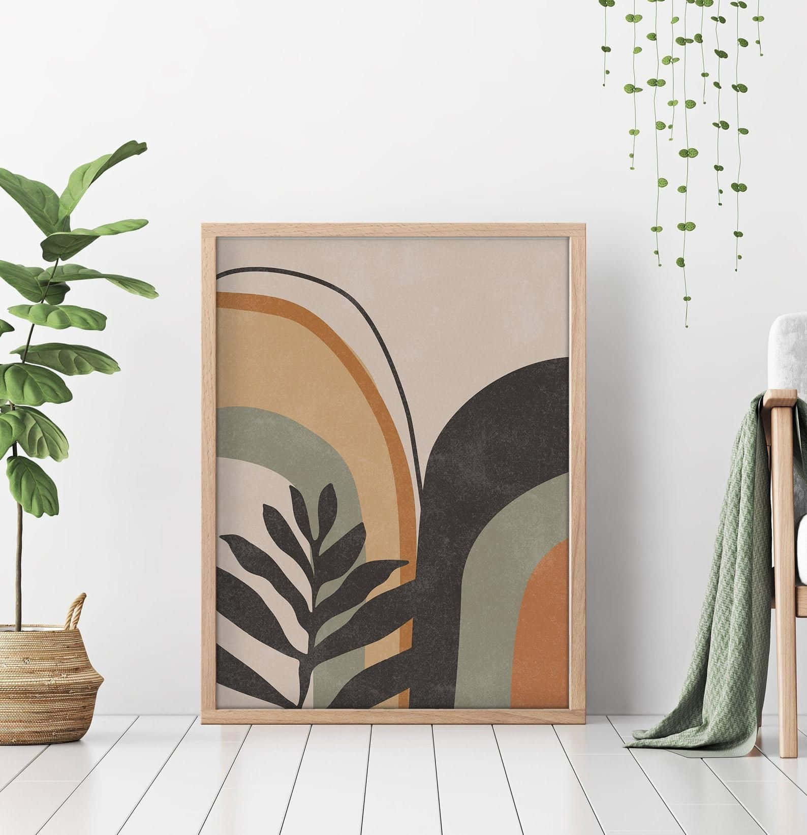 Minimalist Painting 桌布 壁紙 — 一幅帶有彎曲大地色調和葉子剪影的裝框抽象植物藝術品，靠在一面白牆上，旁邊有一棵琴葉榕和懸掛的綠色植物。