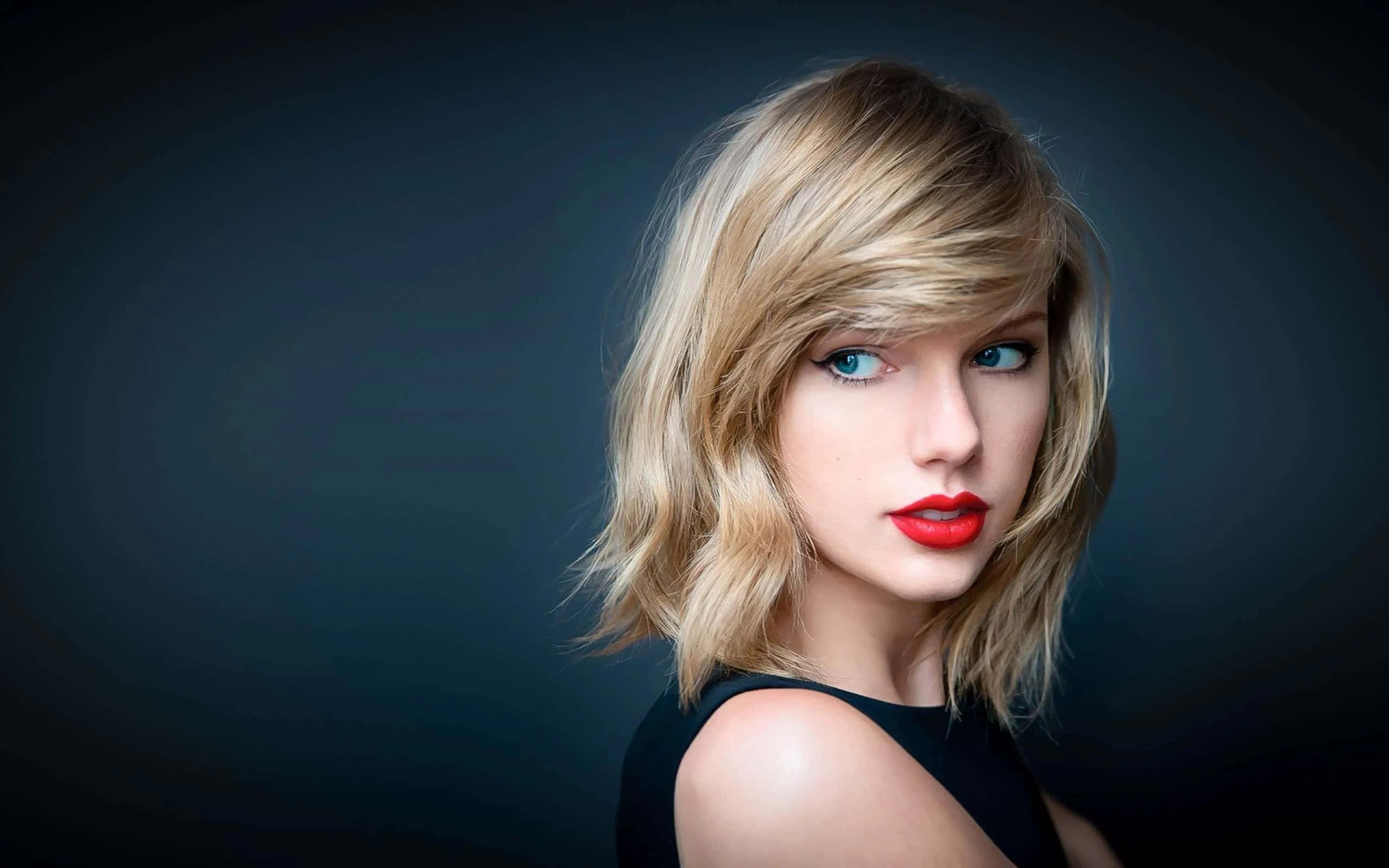 Taylor Swift 桌布 壁紙 — 一幅引人注目的肖像，一位金髮碧眼、紅唇大膽的女性，背景為深色漸變。