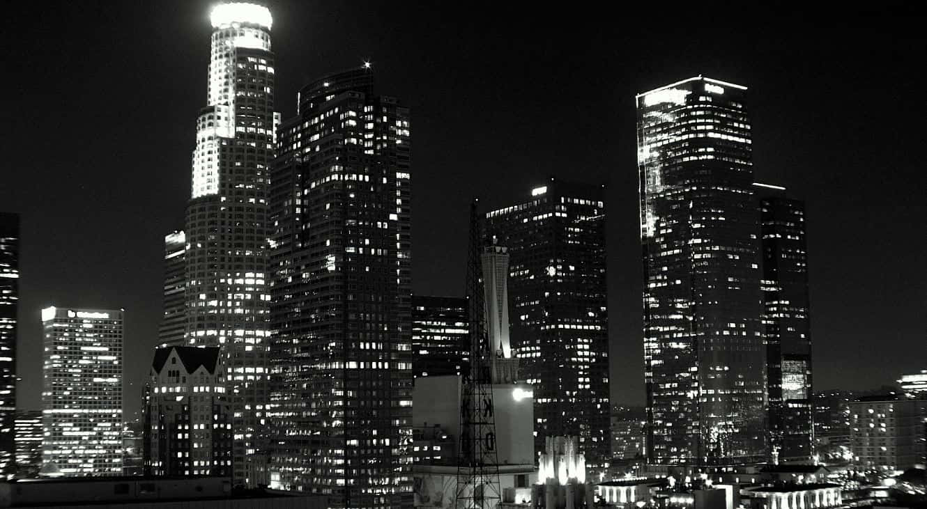 Buildings 桌布 壁紙 — 一幅引人注目的黑白夜景城市景觀，高聳的摩天大樓在黑暗的天空中亮著窗戶。