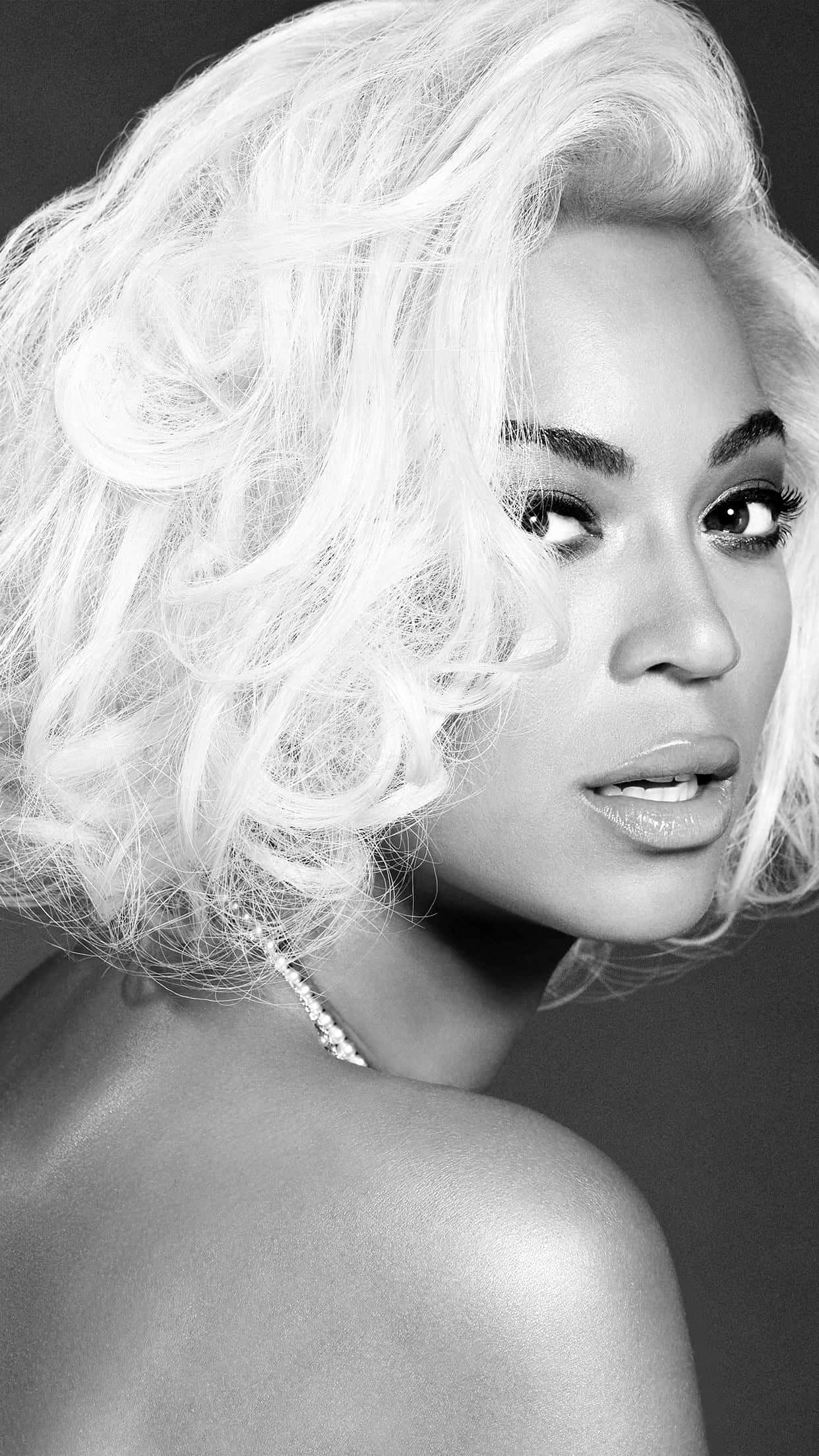 Beyoncé 桌布 壁紙 — 一幅引人注目的黑白肖像，一位擁有豐盈金色捲髮和大膽妝容的女性直視觀眾。