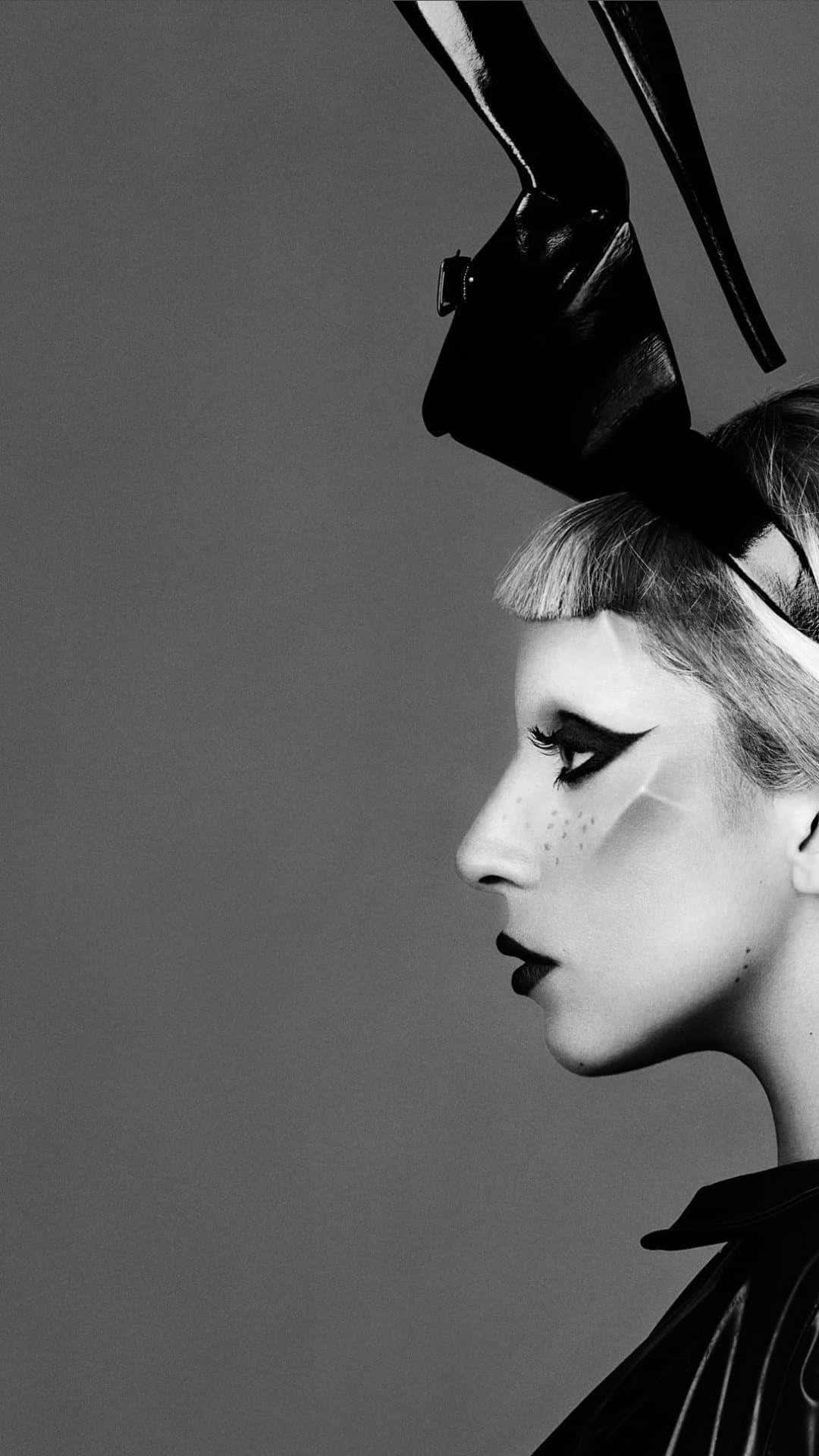 Lady Gaga 桌布 壁紙 — 一幅引人注目的黑白肖像，拍攝一位側面女性，妝容誇張，戴著高聳的雕塑感頭飾，背景為純灰色。