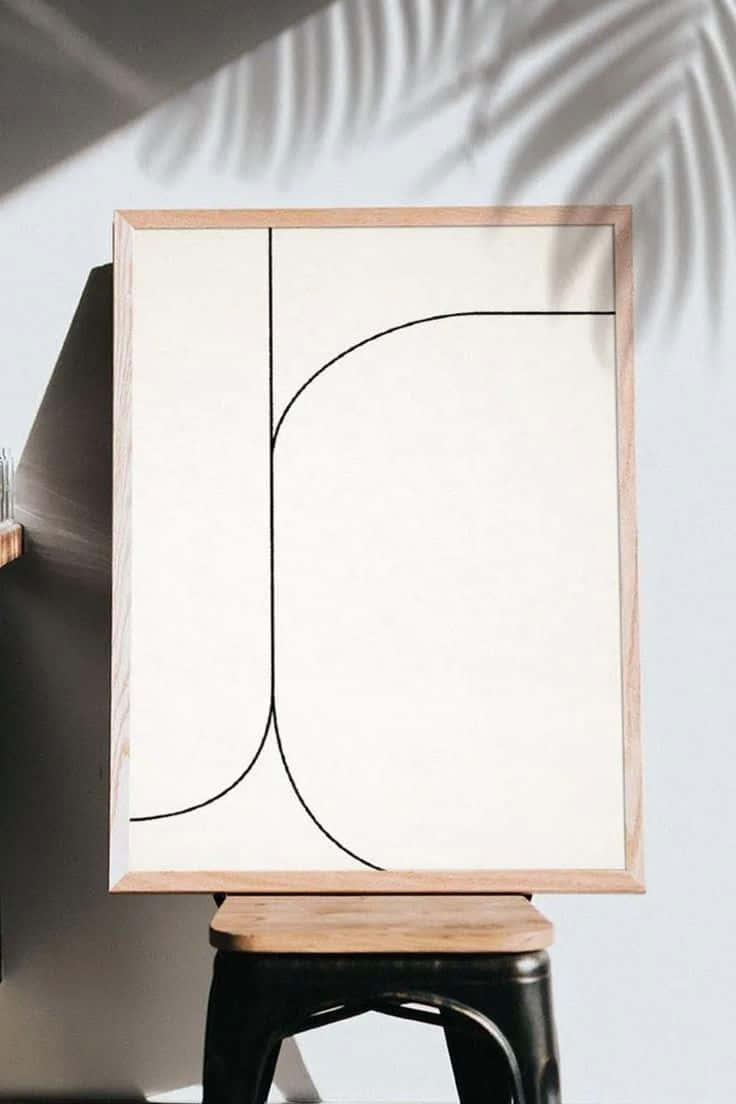 Modern Minimalist Art 桌布 壁紙 — 一幅極簡風格的抽象線條畫作放在凳子上，棕櫚葉的影子投射在白色牆壁上。