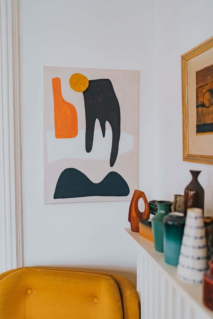 Minimalist Painting 桌布 壁紙 — 一幅現代抽象畫，帶有鮮明的橙色、黑色和黃色形狀，掛在白色牆上，下方層架上擺放著色彩繽紛的陶瓷花瓶和一件芥末黃色的椅子。