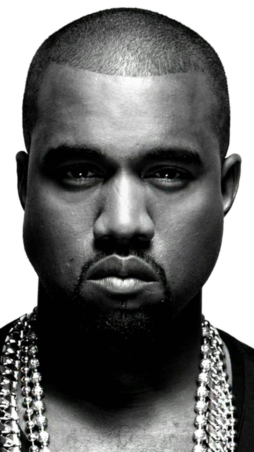 Kanye West In Black Portrait 壁紙 — 一幅鮮明的黑白肖像，Kanye West 帶有強烈的眼神和鑲鑽鏈條，背景簡潔。