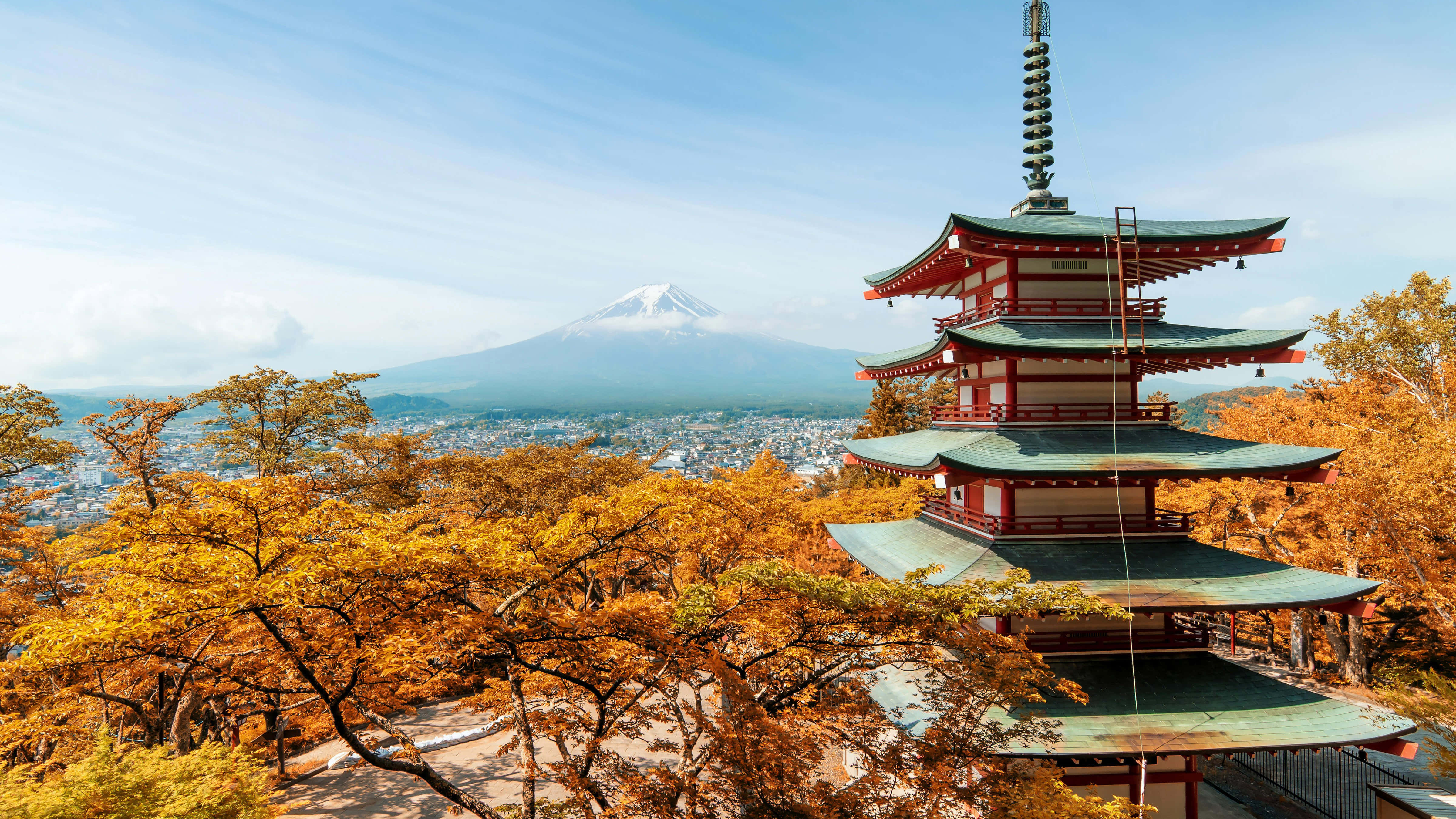 Japanese 桌布 壁紙 — 一座傳統日本寶塔矗立在金黃色的秋樹之中，遠處可見積雪的富士山，在清澈的藍天下。