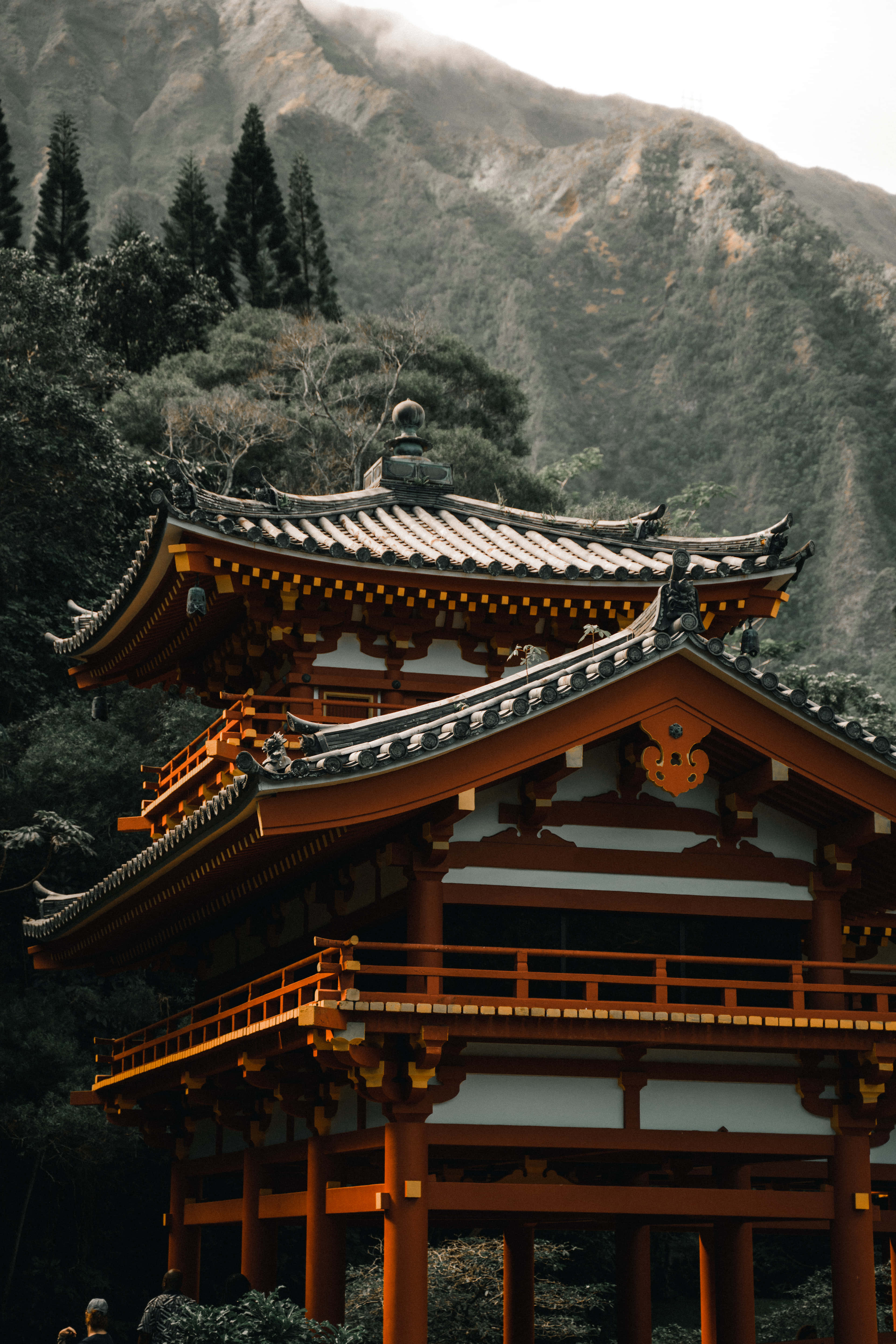 Japanese 桌布 壁紙 — 一座傳統日本寺廟，擁有彎曲的橙色屋頂，在霧氣繚繞的山巒背景下靜靜矗立。