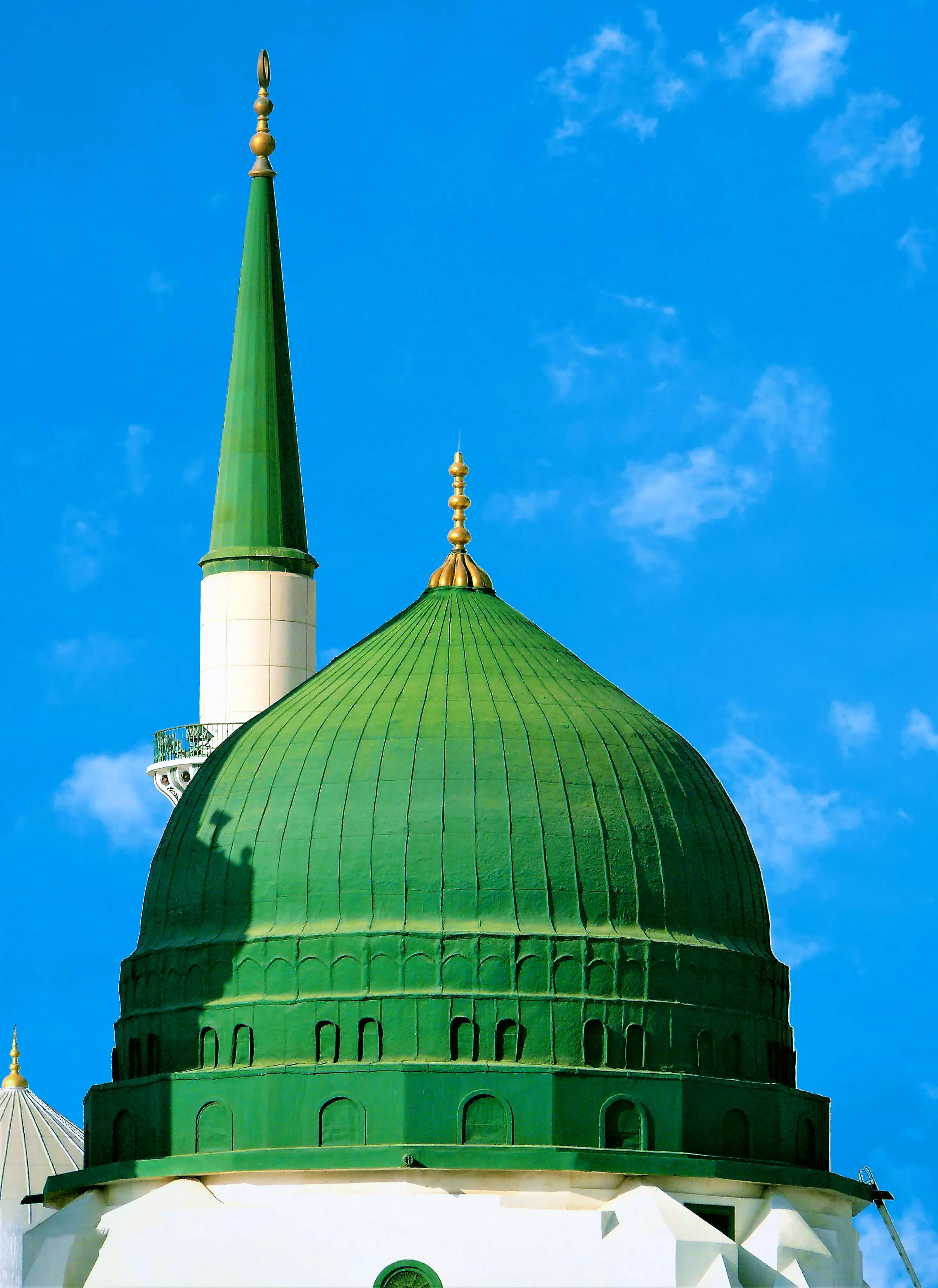 Madina Sharif 桌布 壁紙 — 一座充滿活力的綠色圓頂清真寺，配以相配的宣禮塔，在晴朗的藍天和縷縷白雲中高聳矗立。